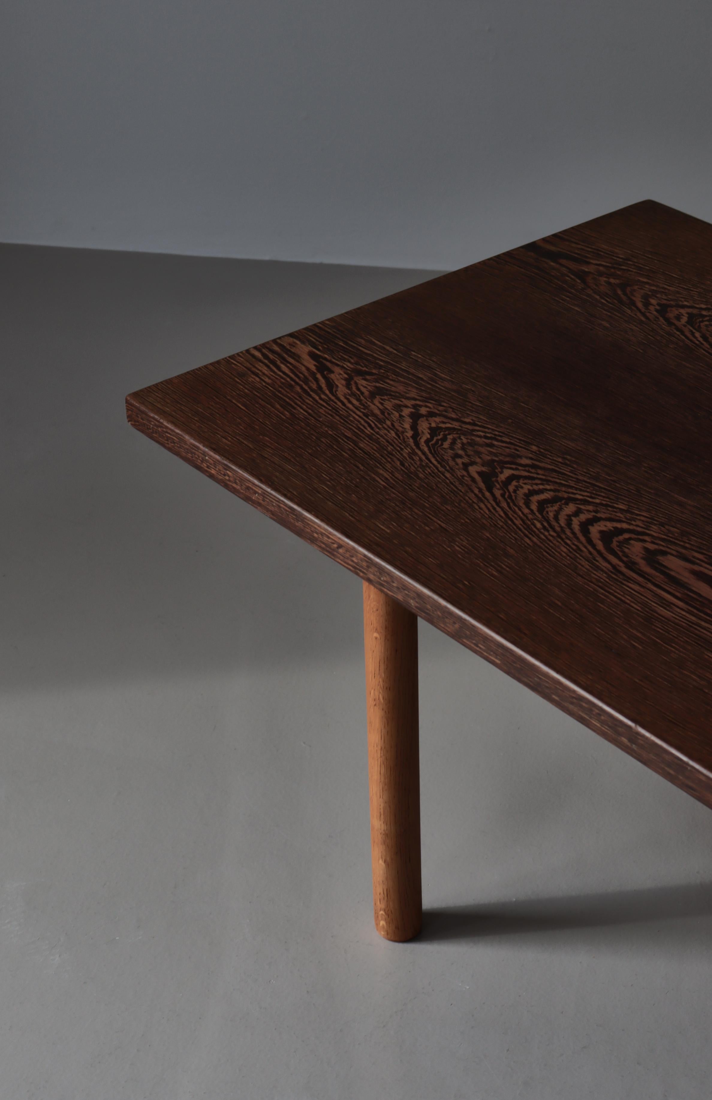 Minimalistic Danish Modern table by Hans J. Wegner. The top is made from hardwood Wenge with an amazing wood grain structure. The legs are made from solid turned oakwood. Manufactured by Andreas Tuck. Stamped underneath.

Furniture manufacturer