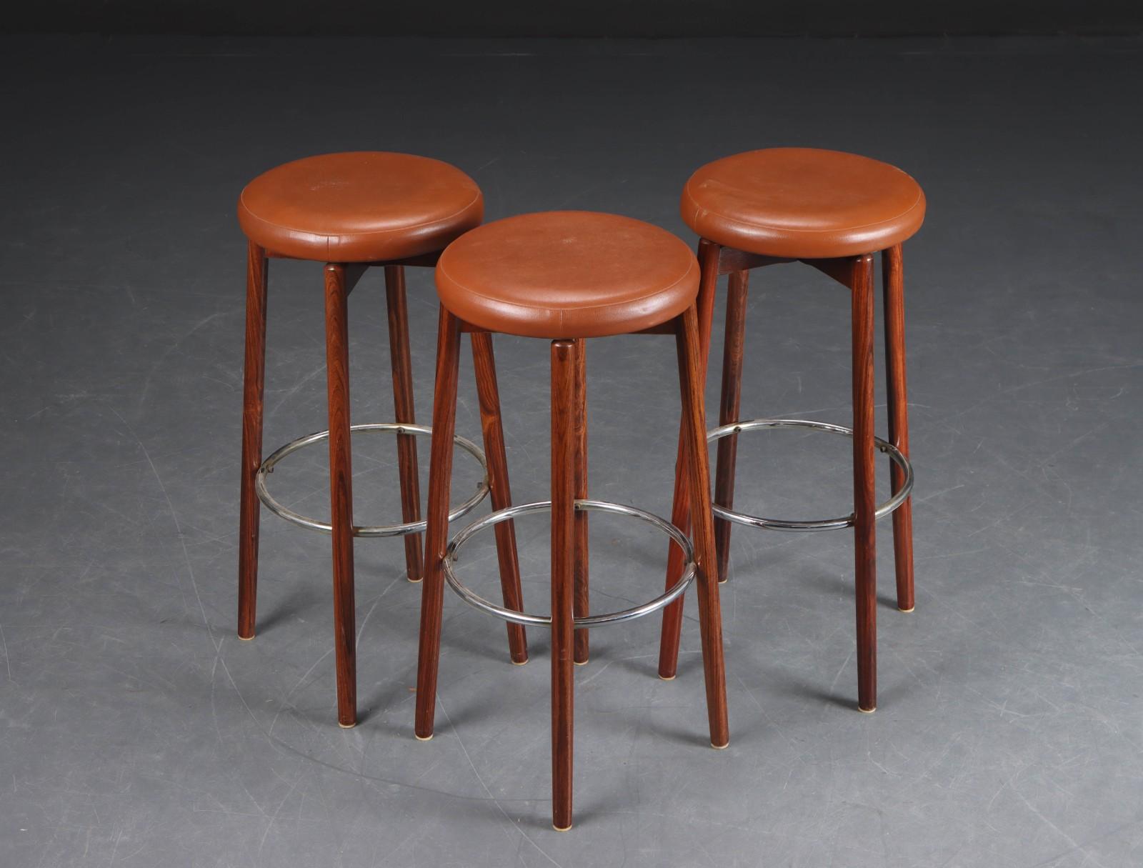 Three bar stools with hardwood frames, 1960s, H 80 cm. Seats upholstered in cognac-colored imitation leather.