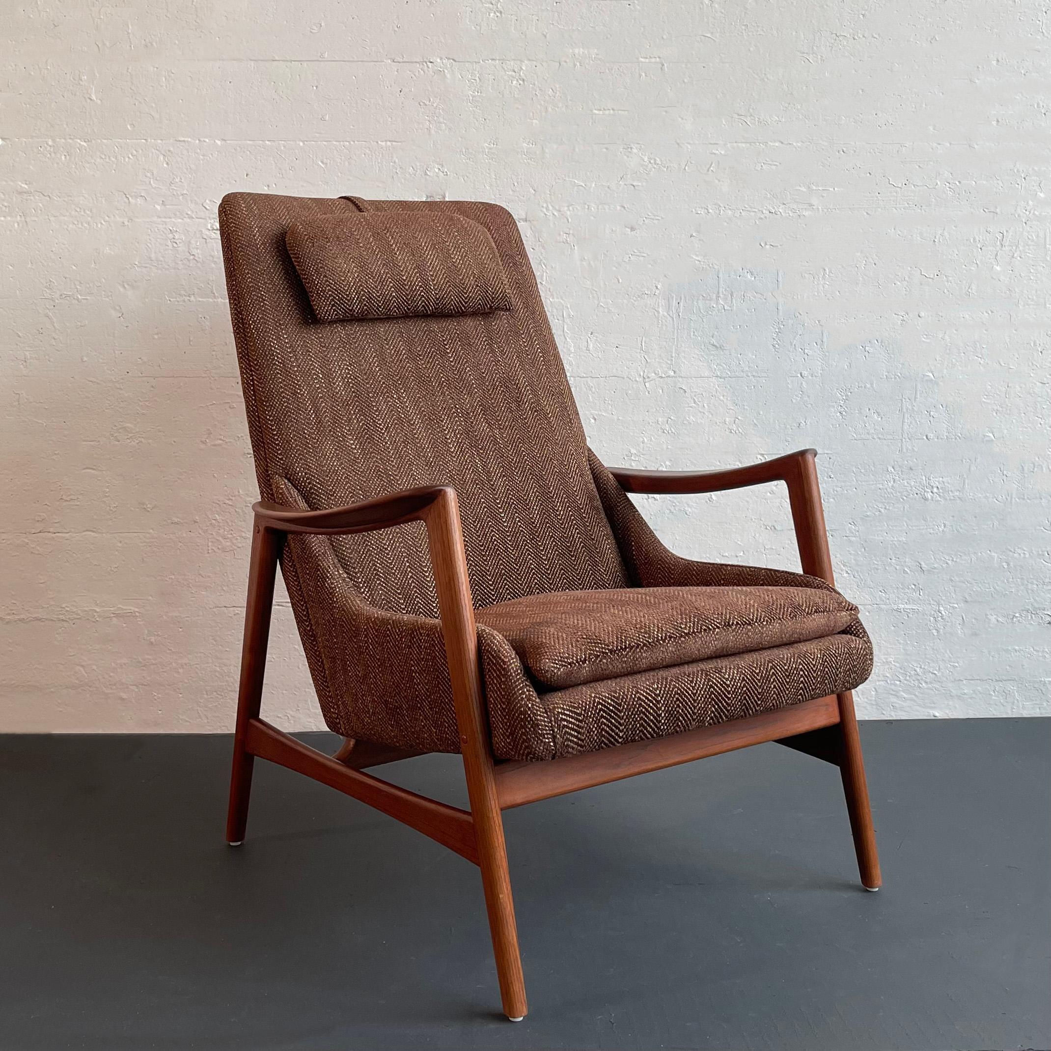 Rare and beautiful Scandinavian Modern high-back lounge chair was designed by Folke Ohlsson and manufactured by Dux in Sweden. This comfortable lounge chair features a solid teak frame that cradles the upholstered seat and supportive head cushion