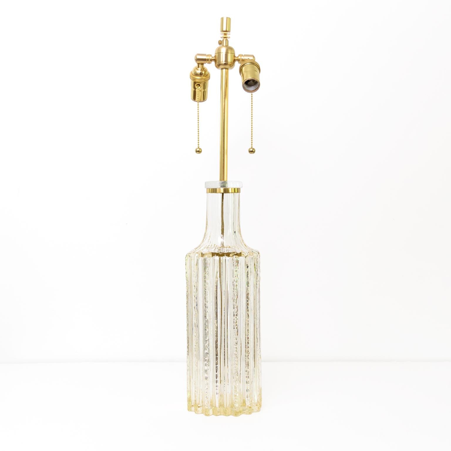 A tall highly textured Scandinavian Modern glass table lamp circa 1960’s with fluted channels in tinted clear glass. The lamp has been newly wired for use in the USA with all brass hardware including a double socket cluster. A polished brass
