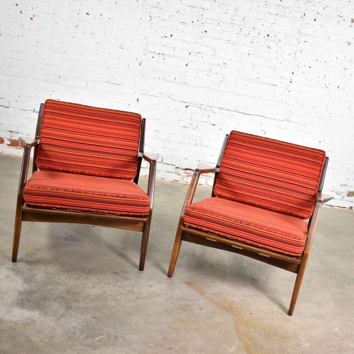 Handsome pair of Scandinavian Modern Selig lounge chairs designed by Ib Kofod-Larsen. They are in wonderful restored condition. The frames have been refinished, the strapping is new, and new cushions have been made and upholstered in a NOS (new old