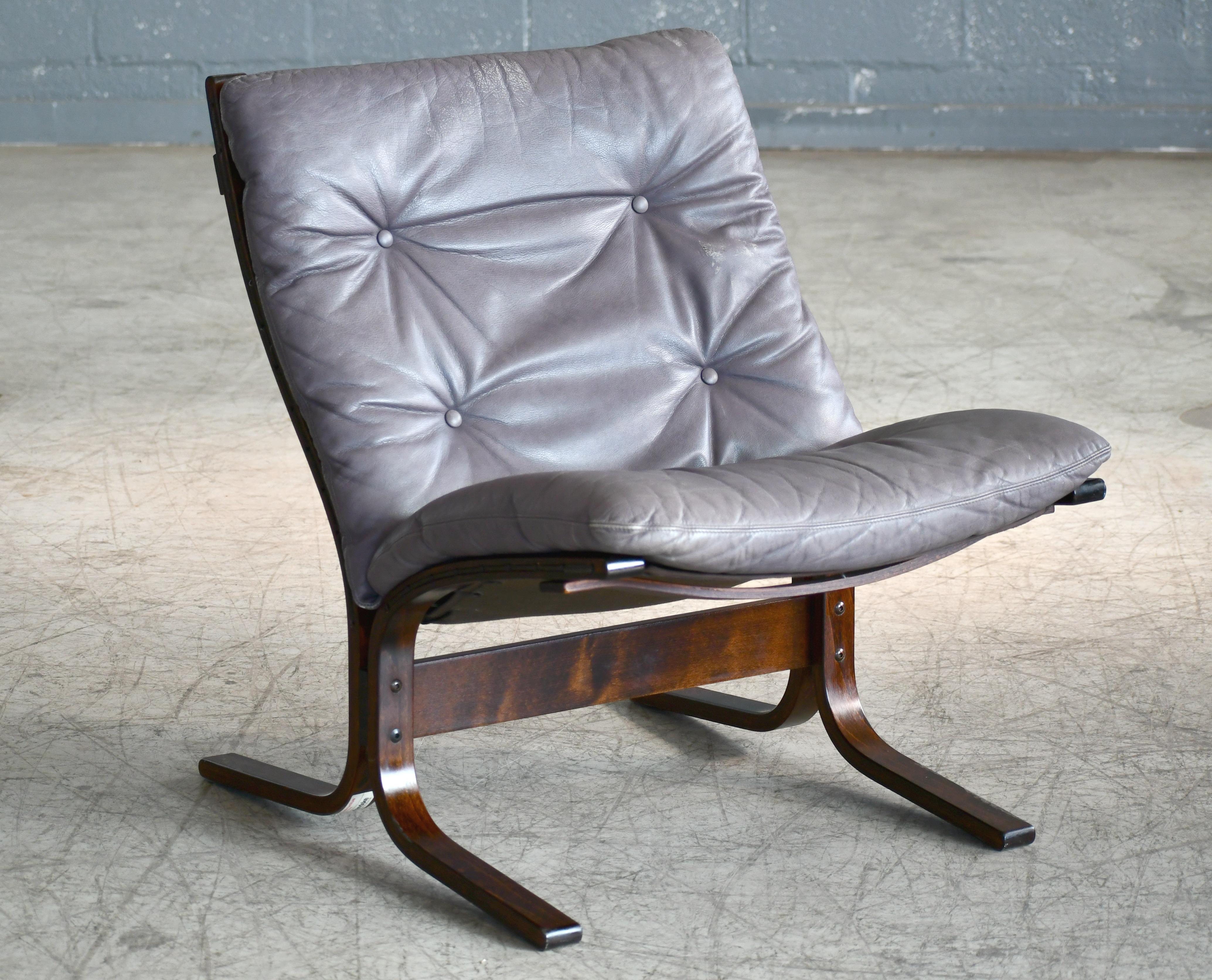 Great lowback Siesta chair grey leather with matching ottoman and dark stained bentwood frame. Designed by Ingmar Relling in the late 1960s and manufactured by Westnofa of Norway. The cushion made of top grain leather has obtained a very nice patina