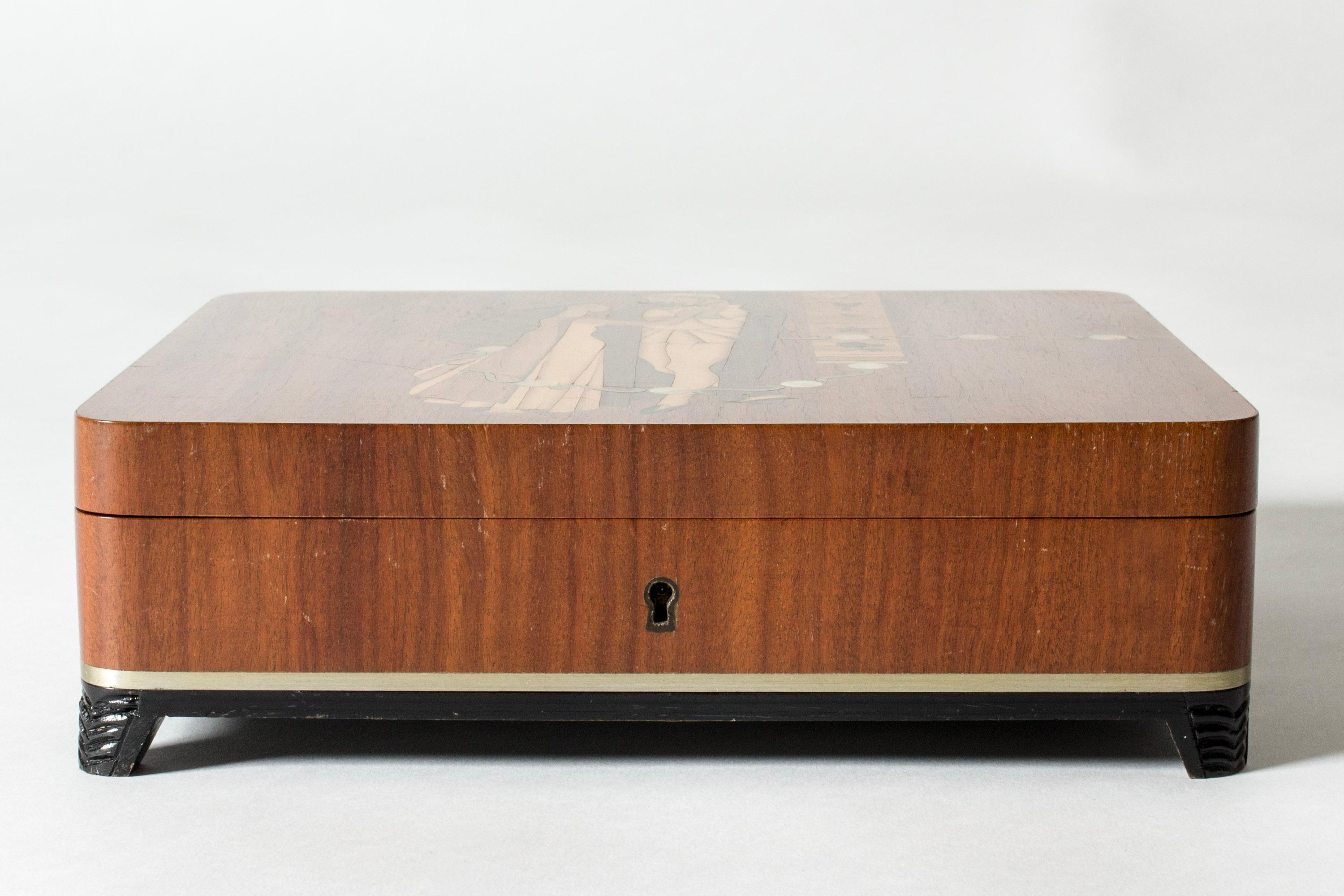 Jewelry box from Mjölby Intarsia. Made from different kinds of wood with contrasting nuances. Beautiful motif of a man and a woman, where the man is giving the woman a ring. Inside with compartments, dressed in deep red velvet.