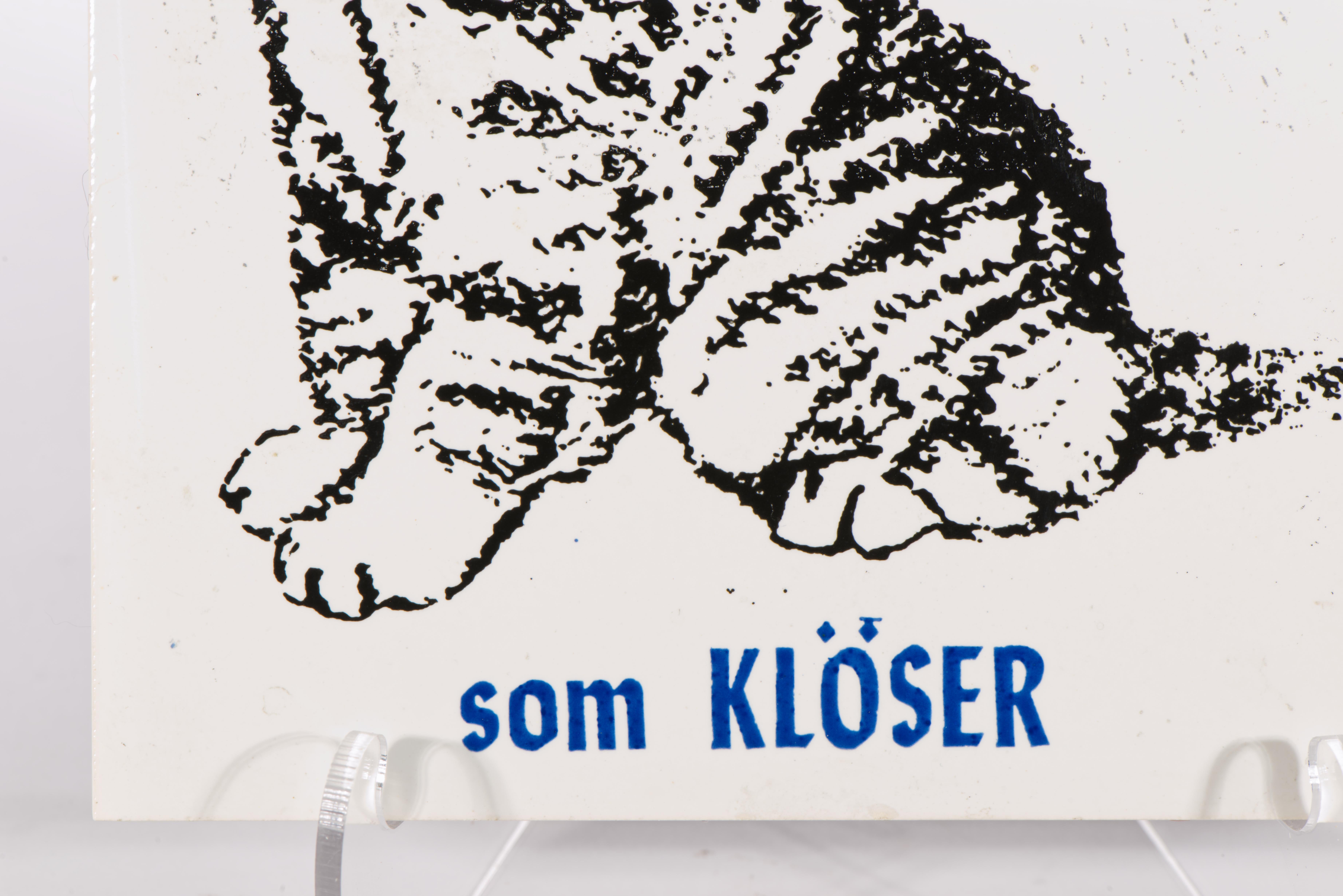  Carreau décoratif ou plaque murale vintage fait à la main représentant un chaton tabby avec un contour noir sur un fond de céramique ou de porcelaine blanc cassé, avec un texte bleu marine en suédois. Le texte dit 