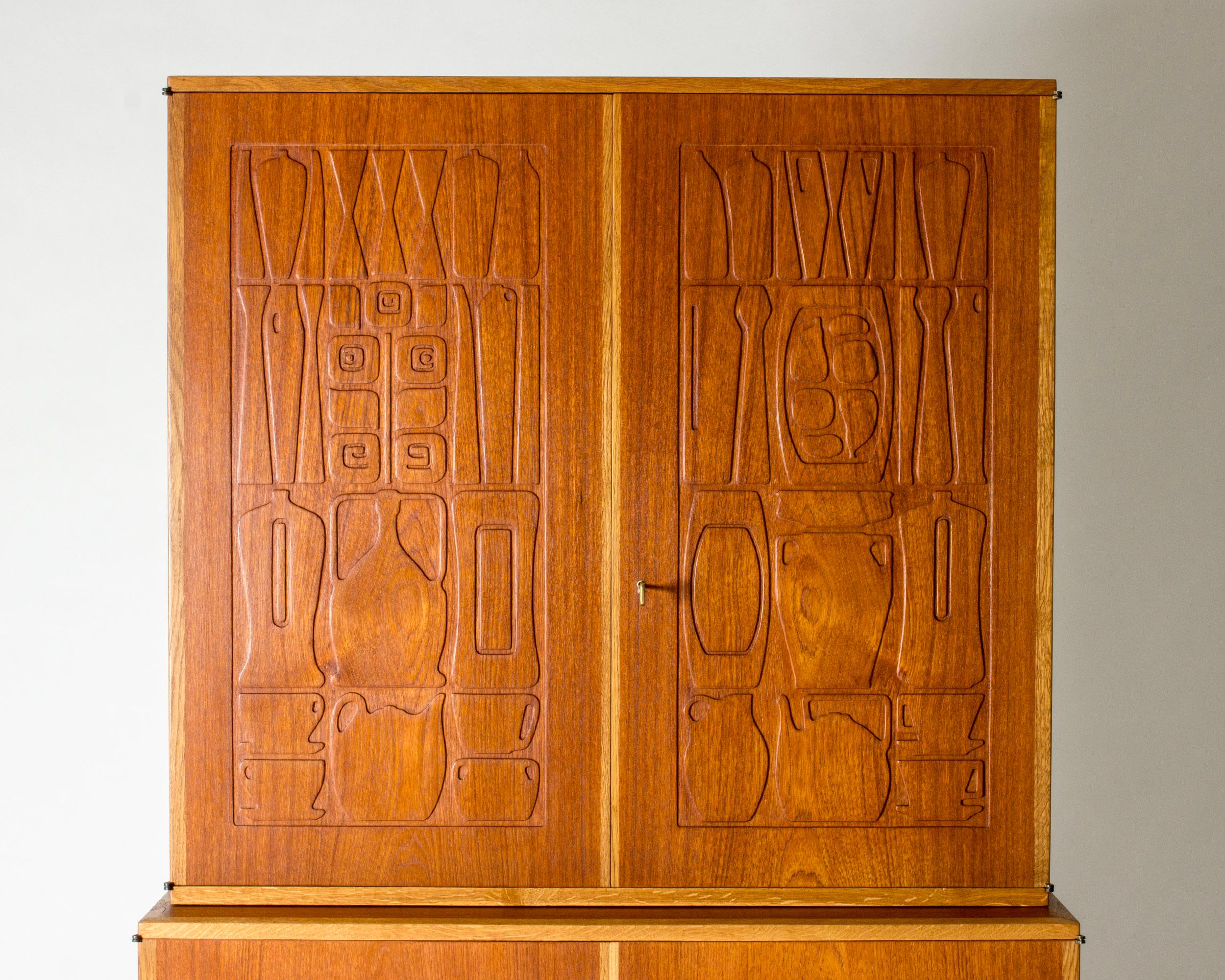 “Krus” (“Vessel”) cabinet by Yngve Ekström, made from teak. The front doors display a modernistic relief of everyday kitchen objects mixed with flowers and decorative objects. An arty, humorous suggestion of how to store pots and pans.

