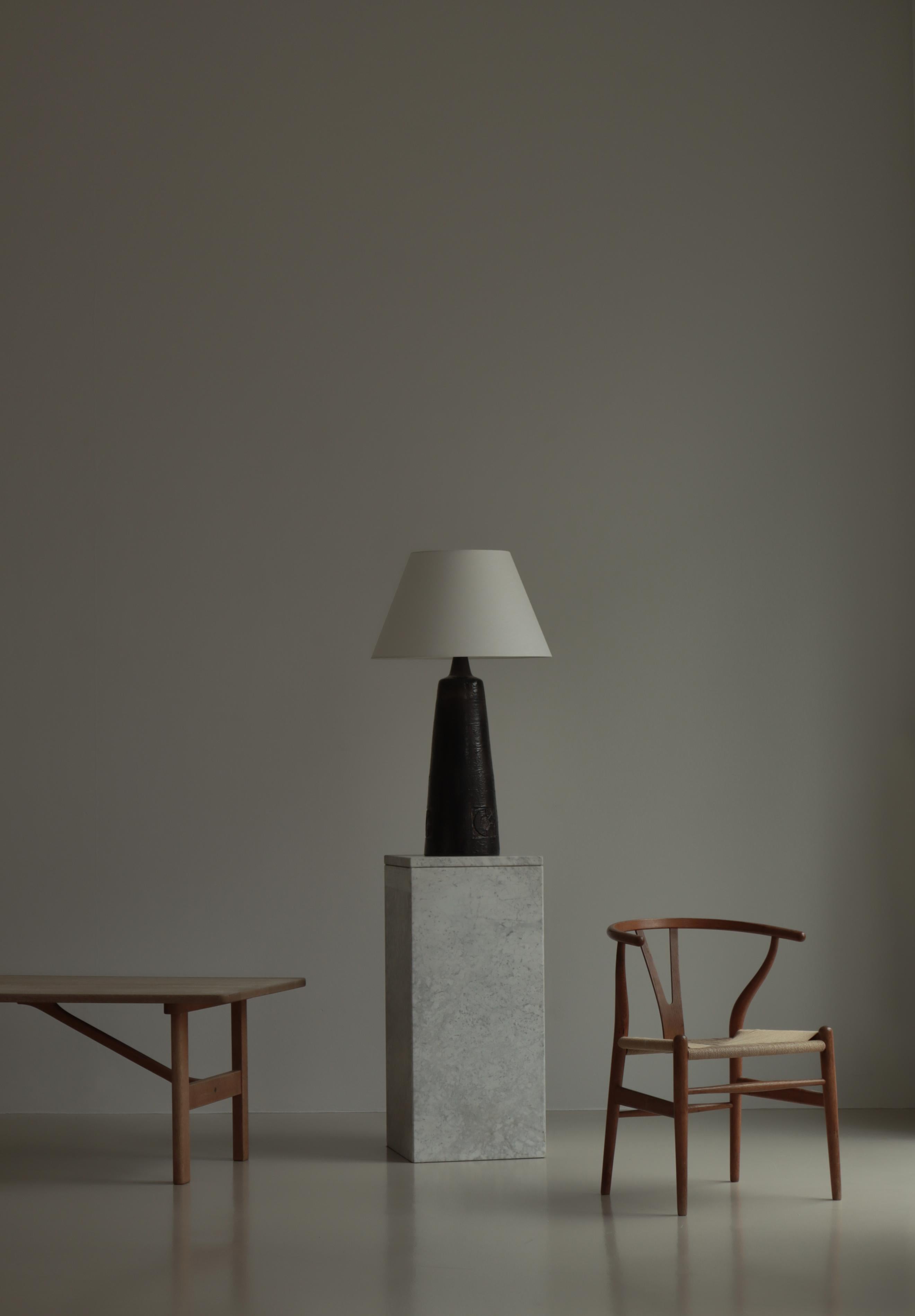 Grande lampe conique en grès de Sejer Keramik, Danemark, fabriquée dans les années 1960. Le grand corps est émaillé d'une glaçure expressive dans des couleurs de terre sombres et incisé de trois motifs circulaires abstraits. Signé 