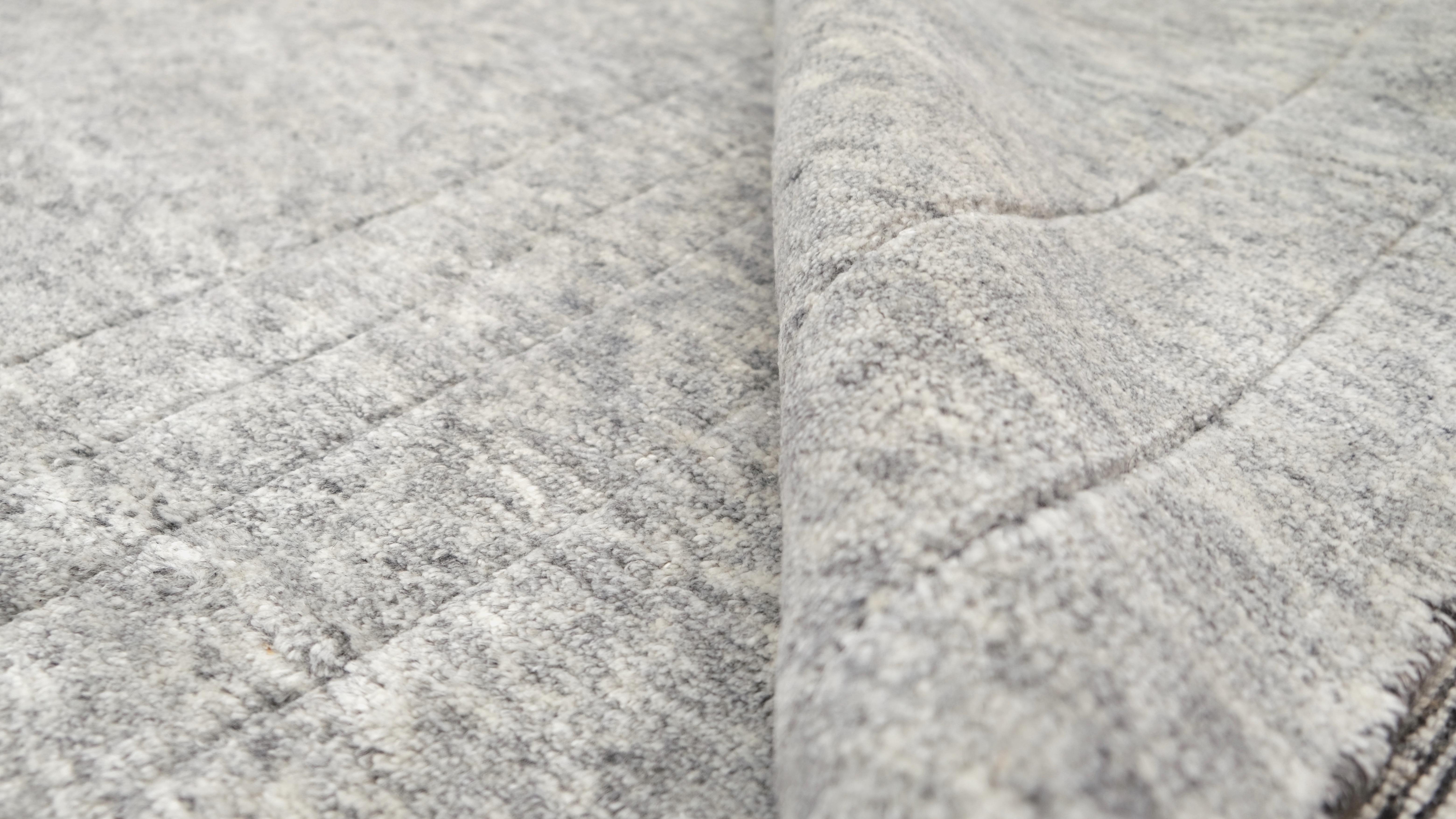 Bringen Sie raffinierte Eleganz in Ihr Zuhause mit diesem handgeknüpften Wollteppich, der ein subtiles geometrisches Linienmuster aufweist. Die weiche, natürliche Graufarbe, ergänzt durch minimalistische Linienführung, schafft eine ruhige und