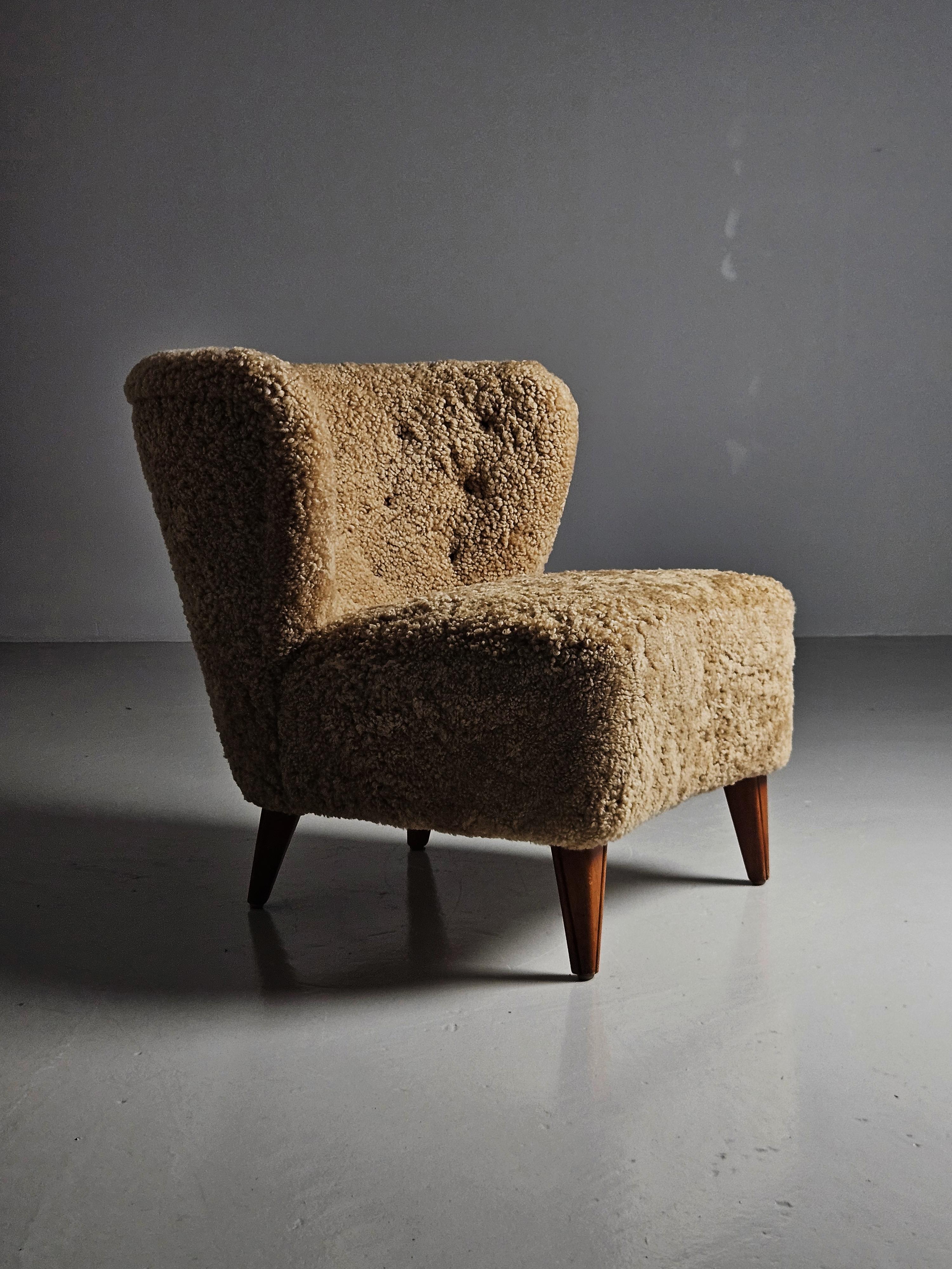 Chunky lounge chair designed and made by Gösta Jonsson, Sweden, during the 1950s. 

Upholstered with honey colored sheepskin. 

Clean modernistic design. Truly a Scandinavian Modern piece. 