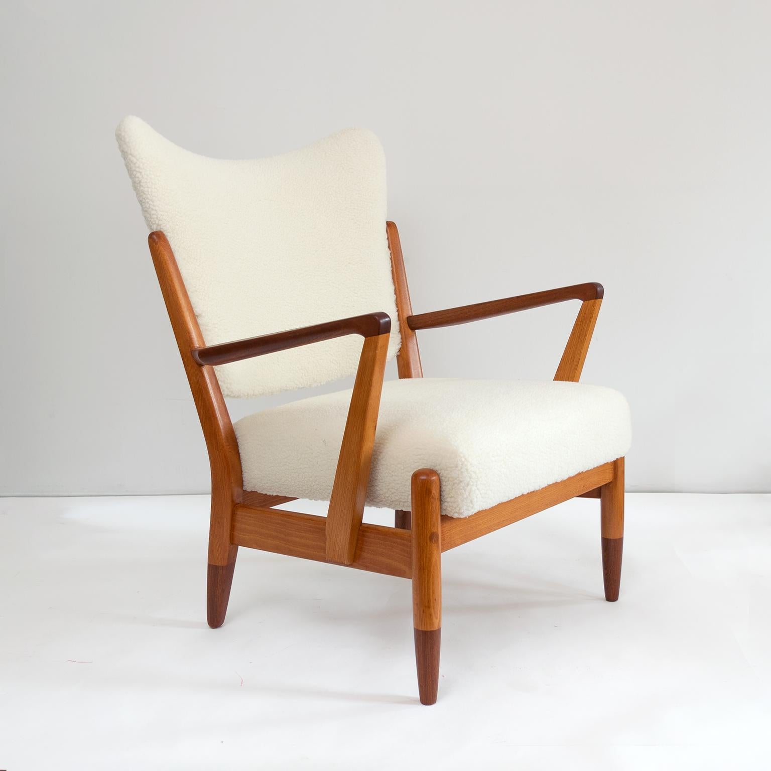 Scandinavian Modern solid elm wood lounge chair with carved teak arms and partial teak legs. Newly restored the chair’s seat and softly curved wingback is upholstered in faux lambs skin fabric. 

Measures: Height 34