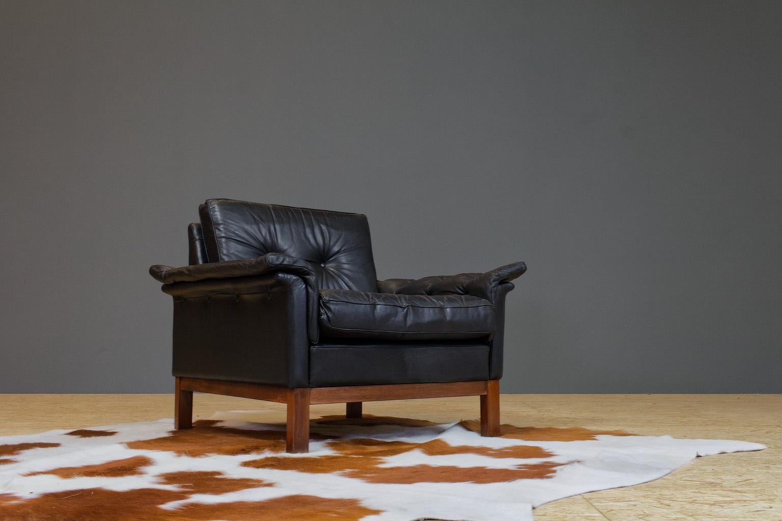 Scandinavian Modern comfortable and luxurious lounge chair in original, yet well preserved black leather. Originated from Denmark 1960s. Designer unknown, yet the pieces feature traits of the style of Knut Saeter, Folke Ohlssen or HW Klein. The legs