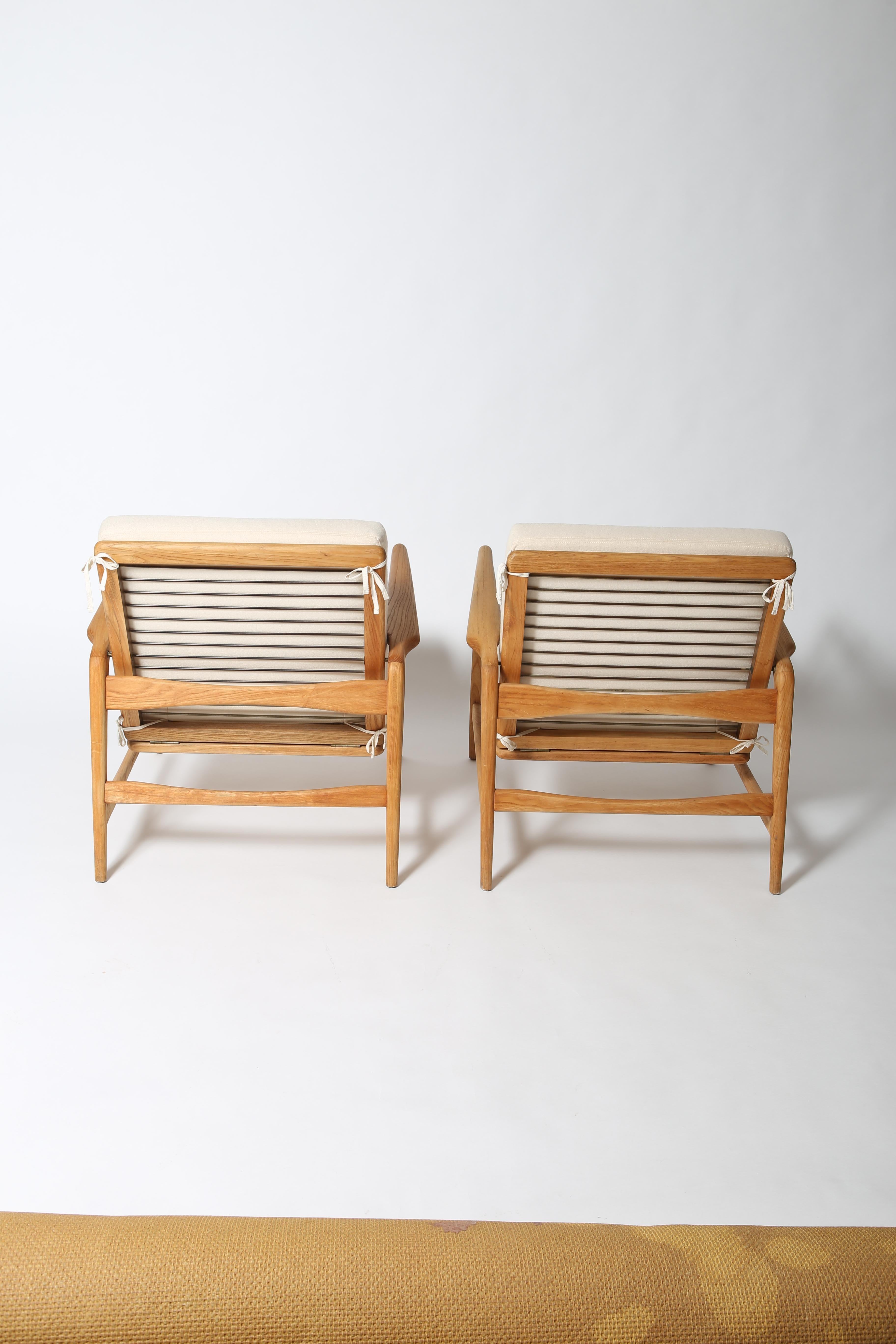 Solid wood lounge chairs in the style of Ib Kofod-Larsen made by Shield circa 1960s. 
Backrest reclines with four comfortable settings and these are fully refinished with minimal use. Ivory wool cushions include cotton ties to mitigate cushion