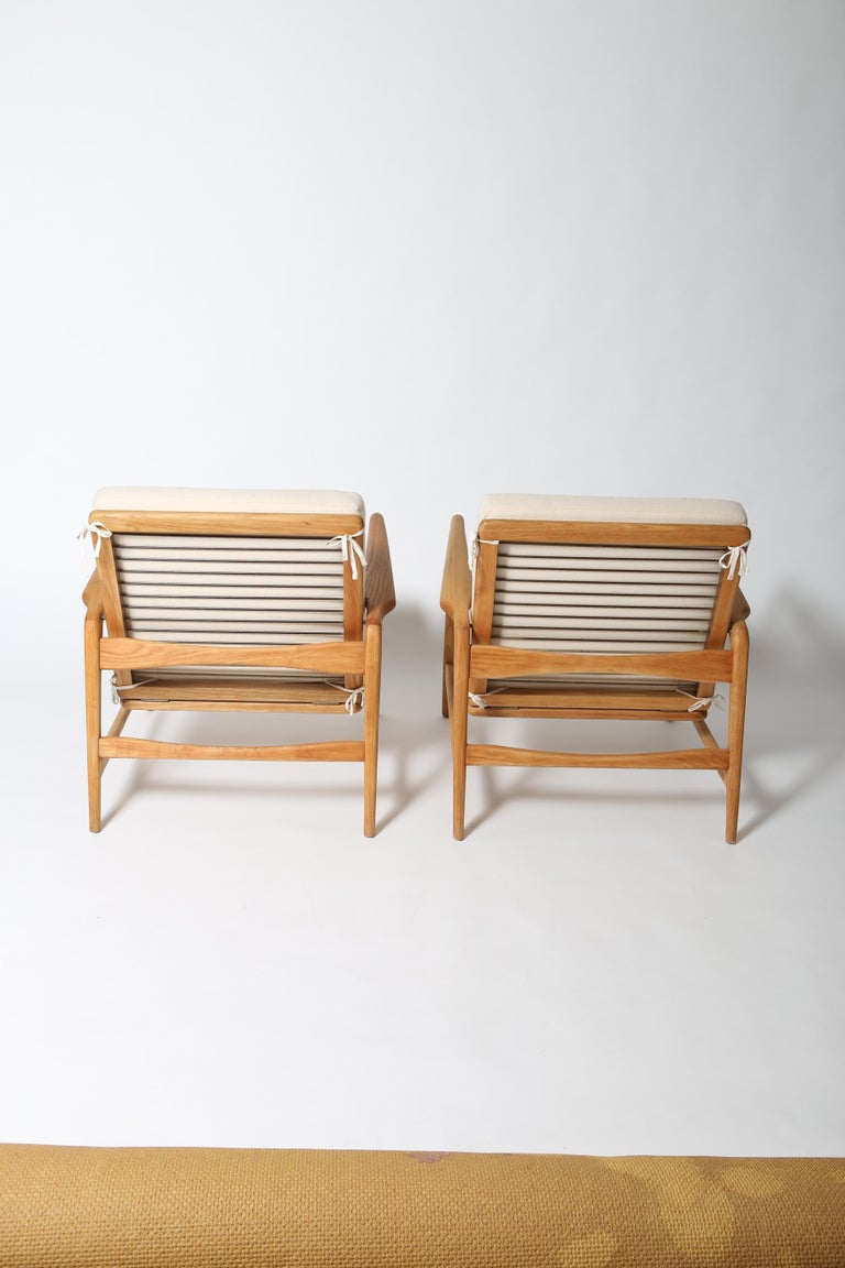 Solid wood lounge chairs in the style of Ib Kofod-Larsen made by Shield circa 1960s. 
Backrest reclines with four comfortable settings and these are fully refinished with minimal use. Ivory wool cushions include cotton ties to mitigate cushion