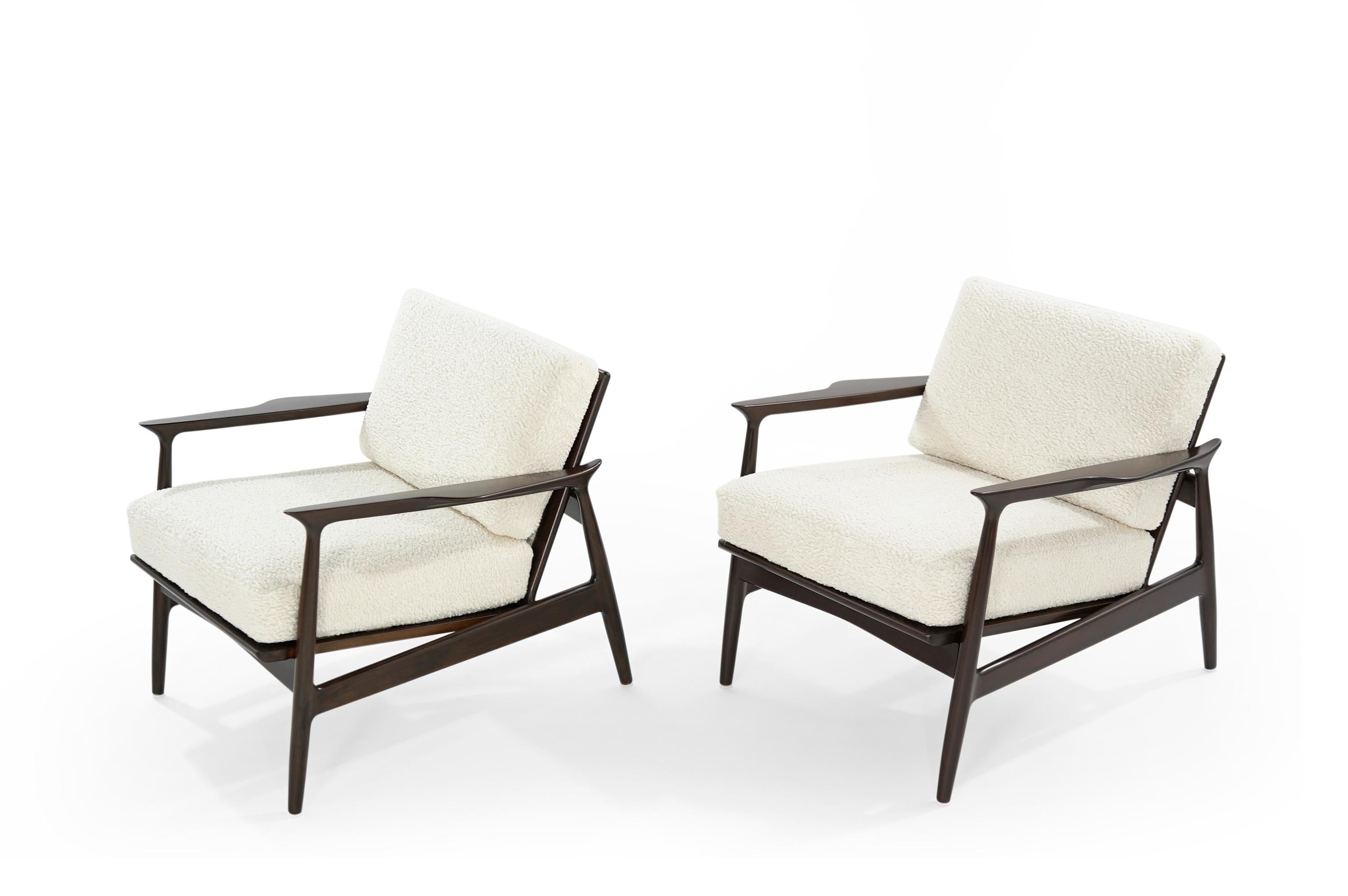 Pair of lounge chairs designed by Danish furniture designers Ib Kofod-Larsen, circa 1950s. Teak framing fully restored and refinished in espresso. Newly upholstered in off-white bouclé. Brass details hand polished.