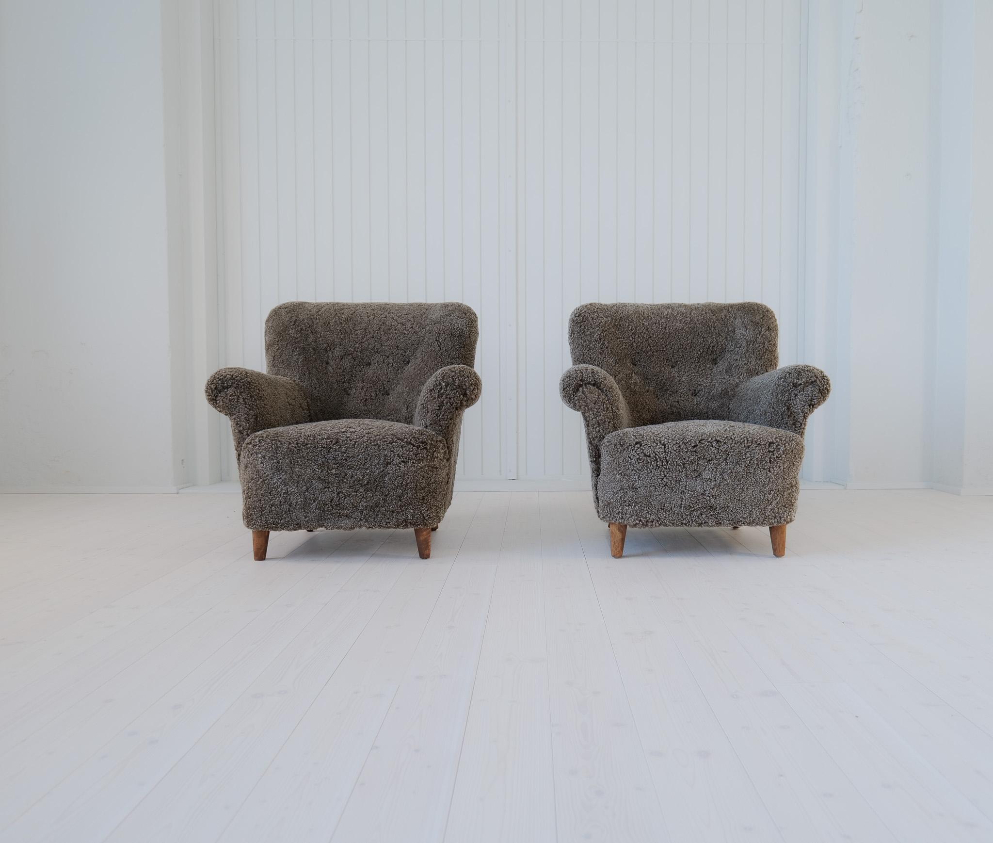 Pair of Swedish modern lounge chairs, with the typical look of its time.
These ones are fully restored and reupholstered with black/grey sheepskin - Shearling.
Beautiful to look at and cozy to sit in. The legs made in stained birch. 

Excellent