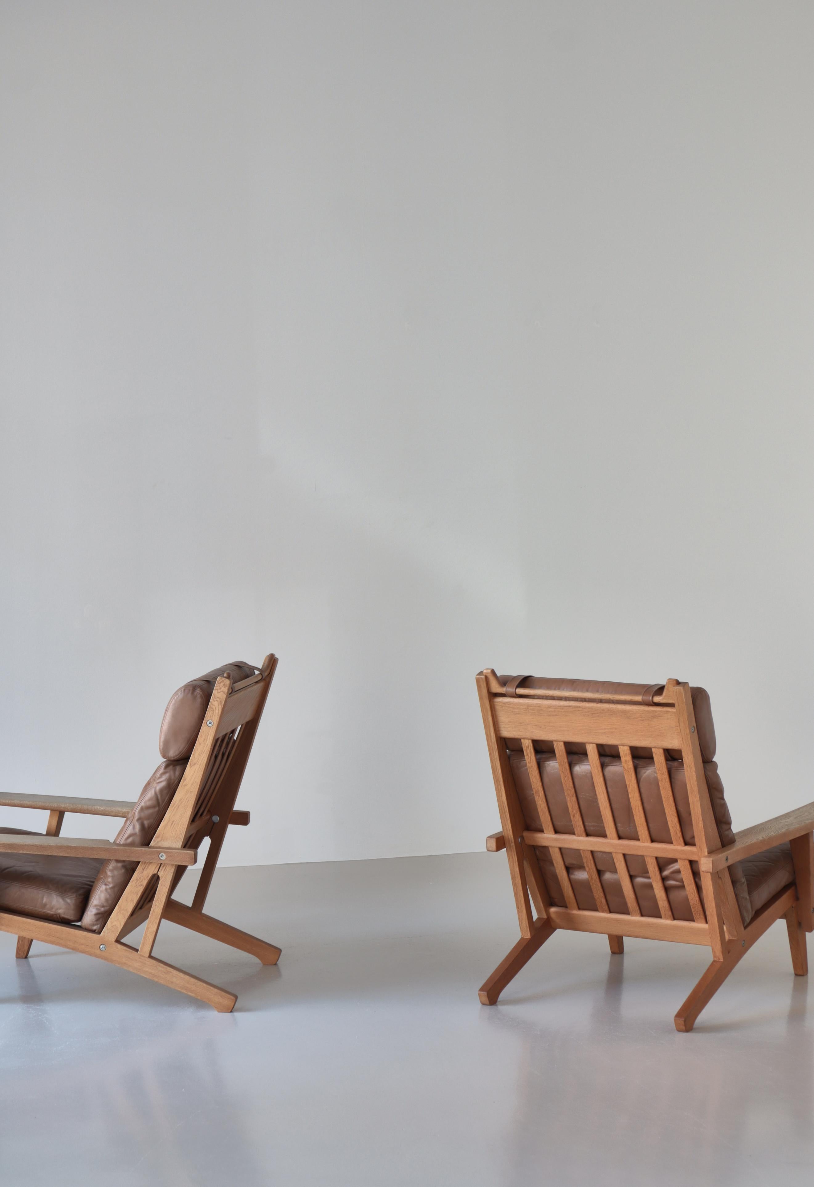 Incredibile set di sedie da salotto modello GE-375 di Hans J. Wegner. Prodotto negli anni '60 da GETAMA in legno massiccio di quercia con una bellissima venatura e patina. Il set conserva i cuscini originali in pelle marrone in buone condizioni. I