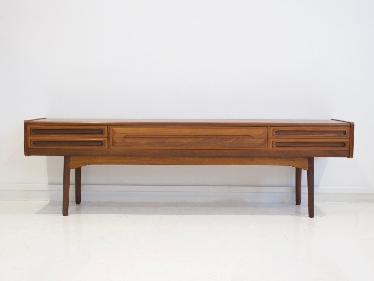 Low sideboard veneered with teak wood, front with five drawers, frame with round inclined tapered legs. Manufactured in Denmark in circa 1960. Side drawers lined with green felt and have compartments for tableware.