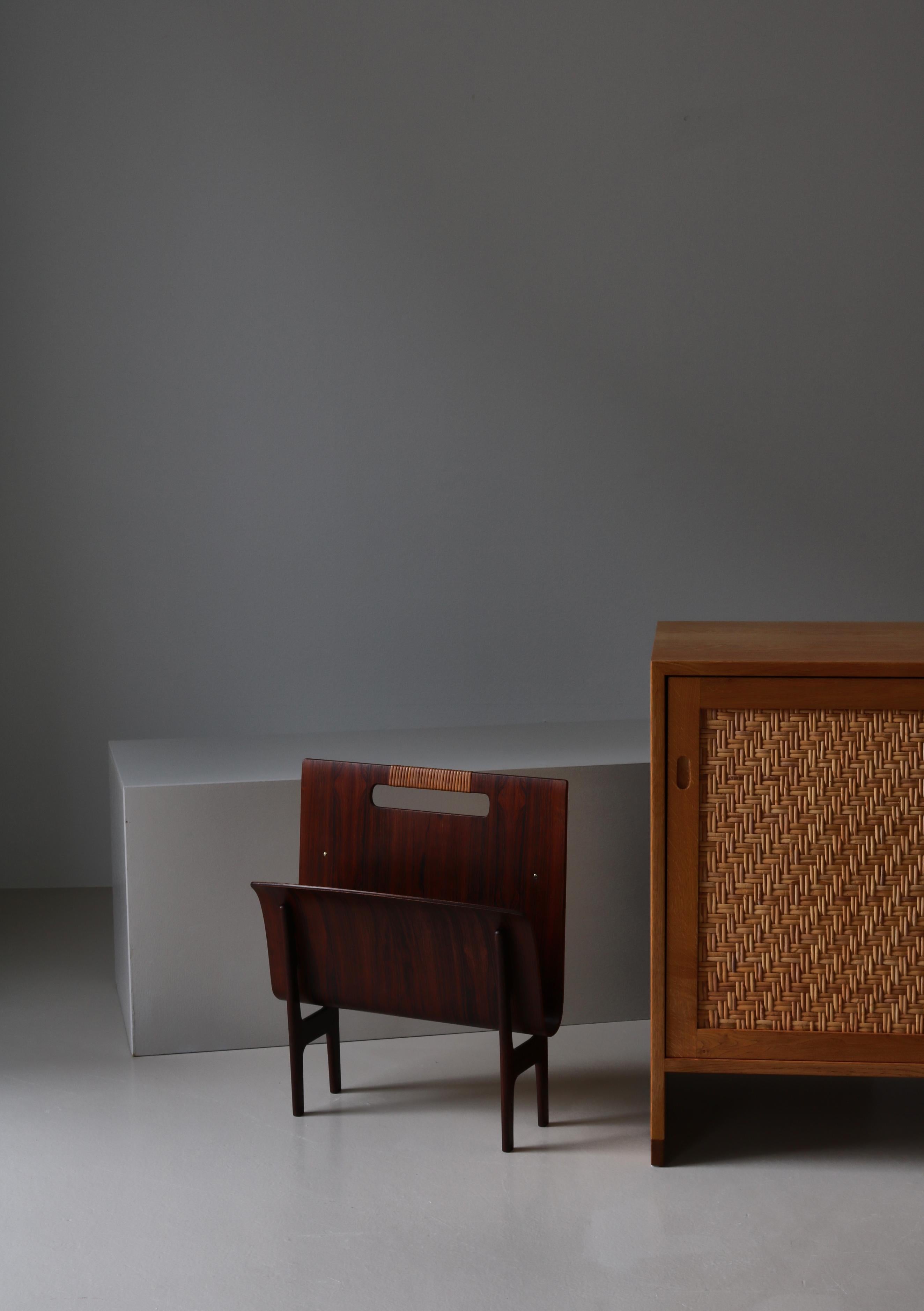 Rare & beautiful magazine stand in rosewood and rattan cane by Danish designers Ejner Larsen & Aksel Bender Madsen. Made in the 1960s. 

Danish design duo Ejner Larsen (1917—1987) and Aksel Bender Madsen (1916—2000) designed some of the most refined