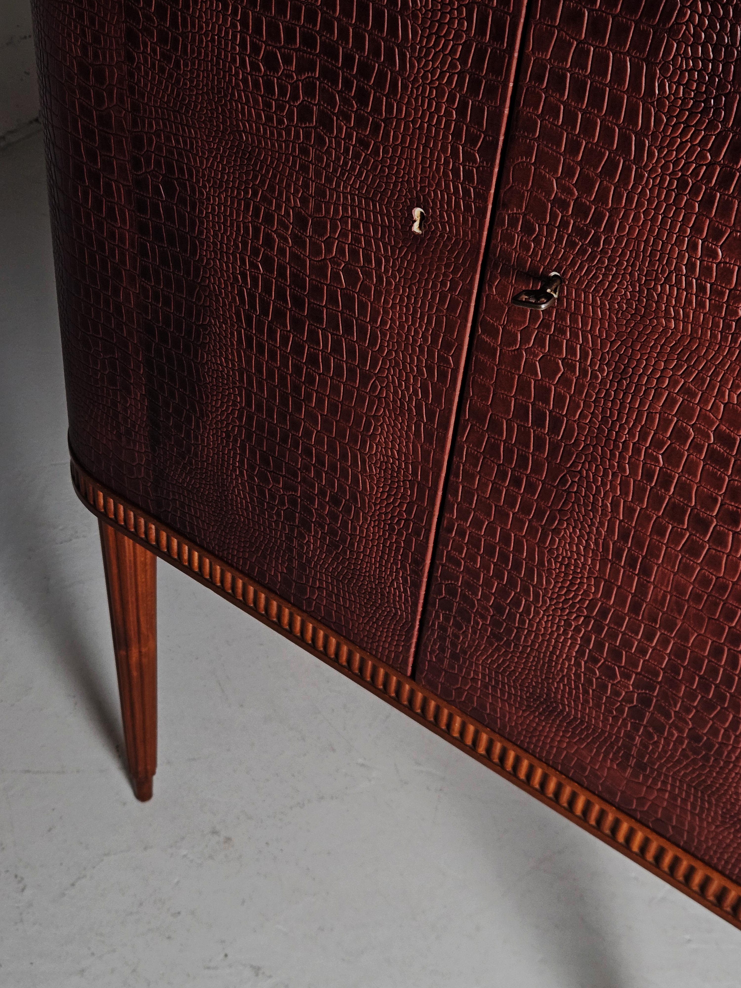 Great bar cabinet by unknown Swedish designer. Produced by AB Förenade Möbelfabrikerna Linköping, Sweden, during the 1950s. 

Made in mahogany with a leather dressed front. Slender sculptural legs. Mirror glass and lighting. 

More cabinets