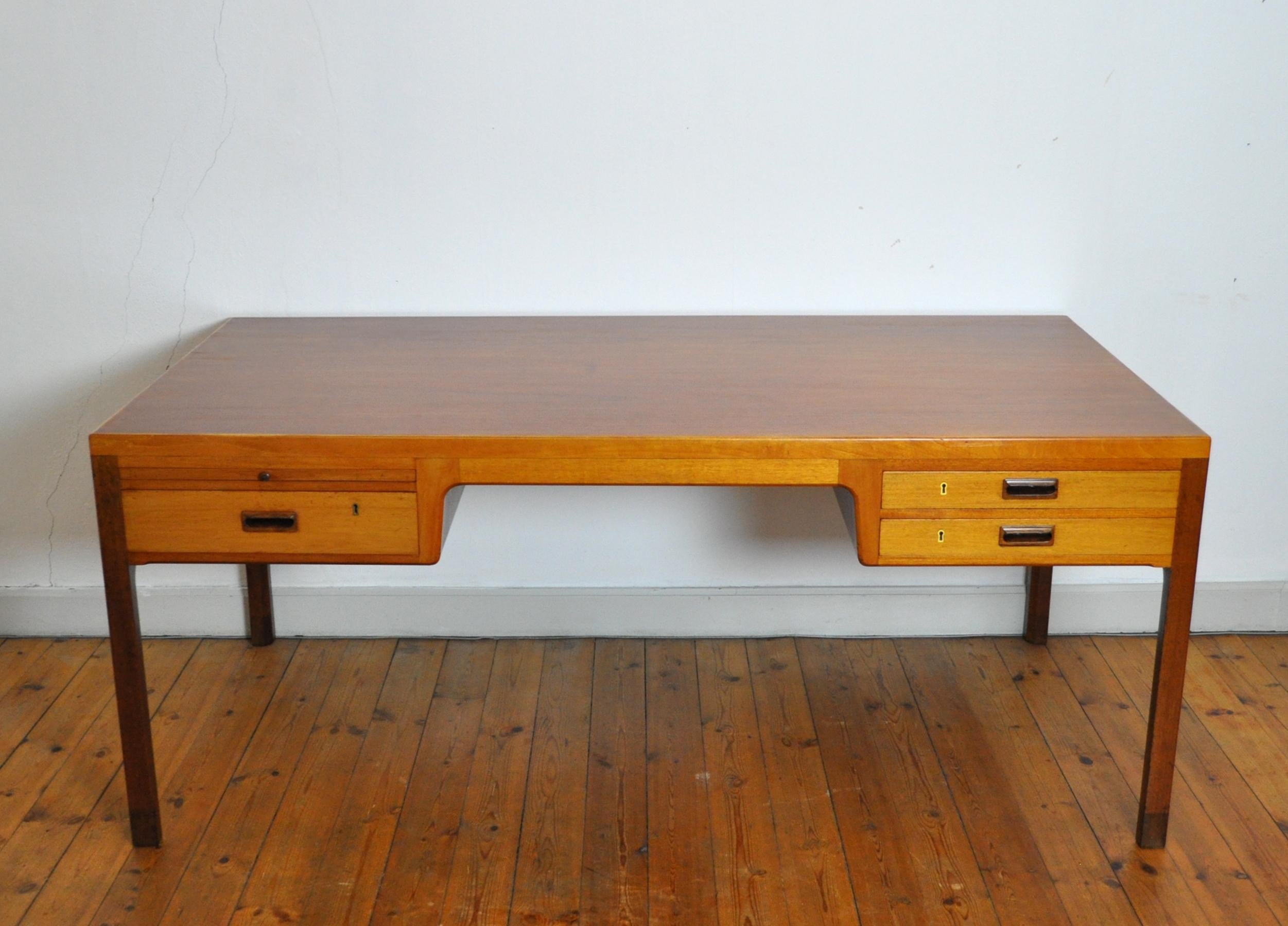 Scandinavian Modern mahogany desk designed by Ejnar Larsen and Aksel Bender Madsen, made by the Danish cabinetmaker Willy Beck in the 1950s. Features three drawers and a pull-out work surface, expressive tipped squared legs and drawer pulls. 66-68