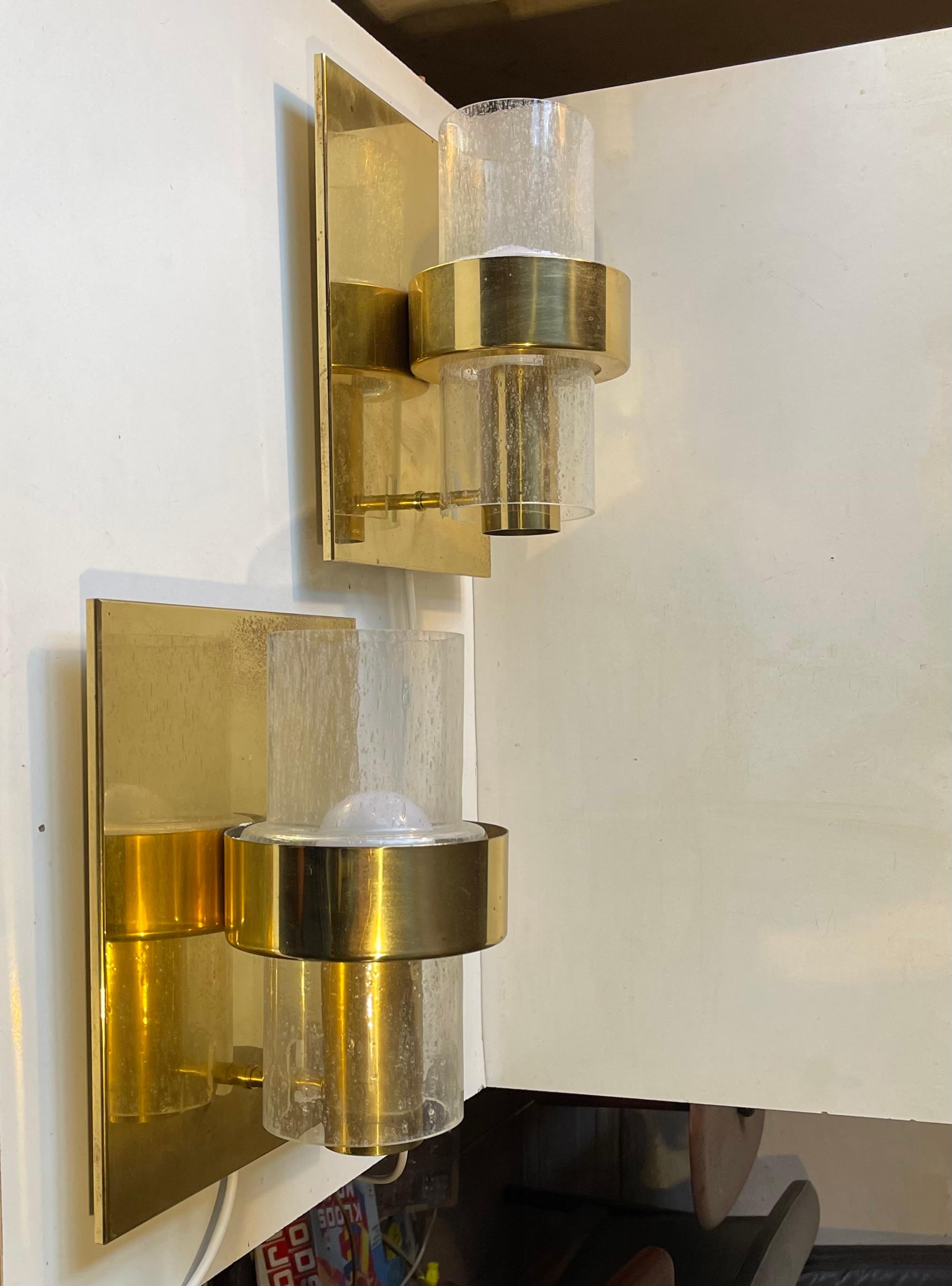 A Pair of 1970s Nautical - Navy sconces composed of brass brackets set with cylindrical hand-blown tubes of rain-effect glass. These lights comes from a Norwegian Navy Ship (No: sjøforsvaret). This model 7360 was designed by Jonas Hidle and