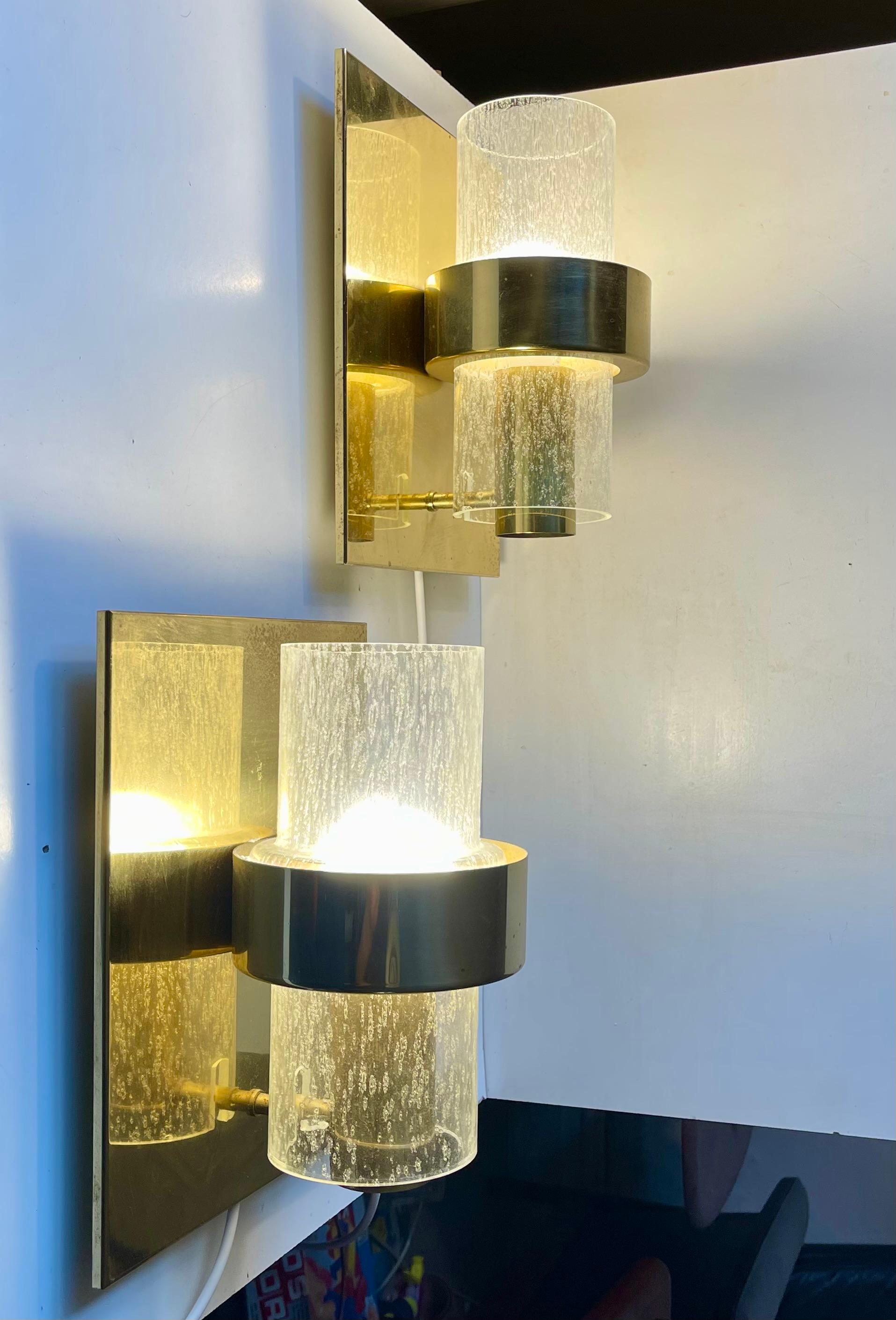 A Pair of 1970s Nautical - Navy sconces composed of brass brackets set with cylindrical hand-blown tubes of rain-effect glass. These lights comes from a Norwegian Navy Ship (No: sjøforsvaret). This model 7360 was designed by Jonas Hidle and