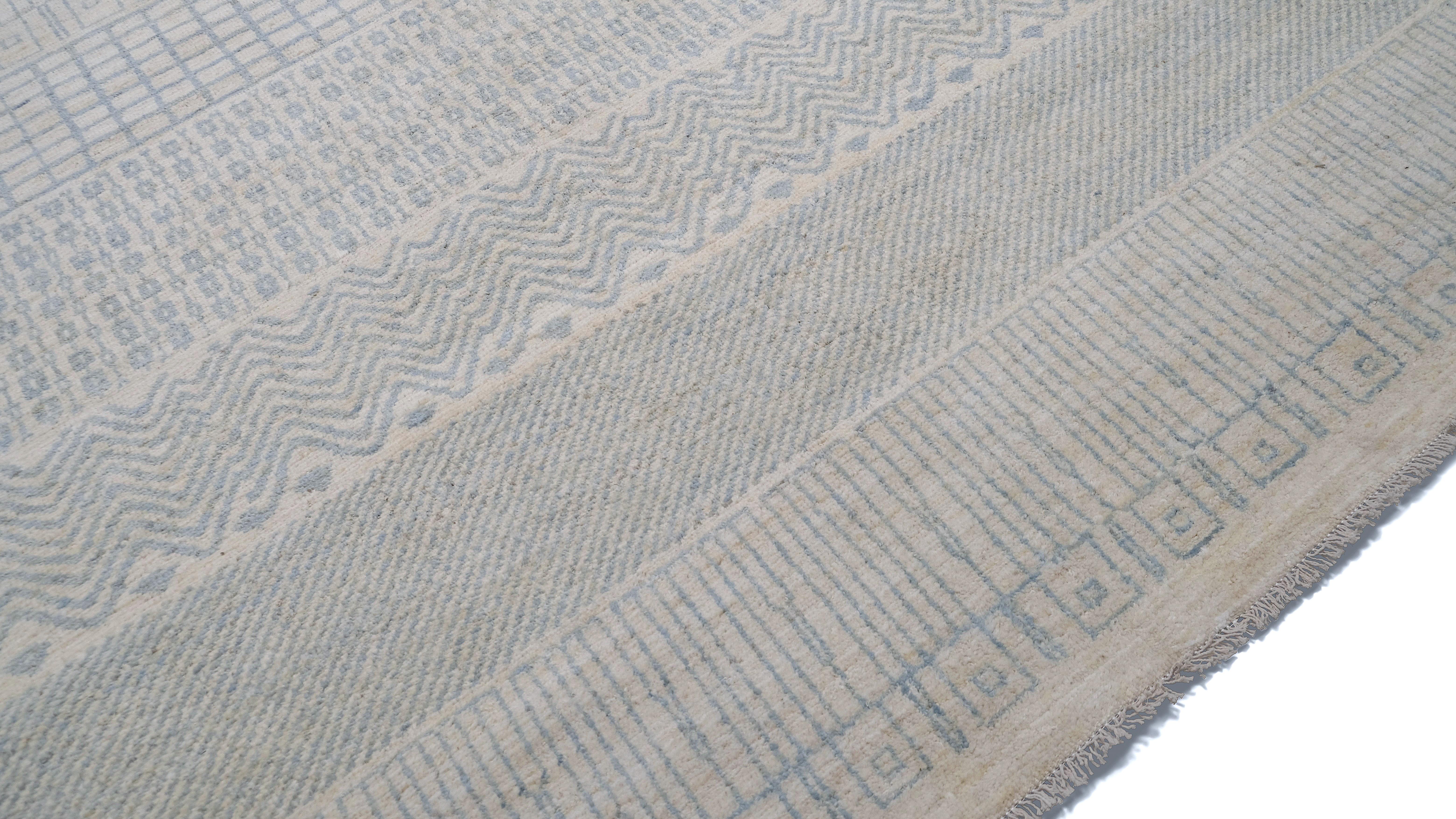 Bringen Sie mit diesem handgeknüpften Wollteppich einen Hauch von moderner Eleganz in Ihr Zuhause. Dieser Teppich besticht durch sein fesselndes Streifendesign mit verschlungenen Mustern in sanften neutralen und hellblauen Tönen. Er verbindet Textur