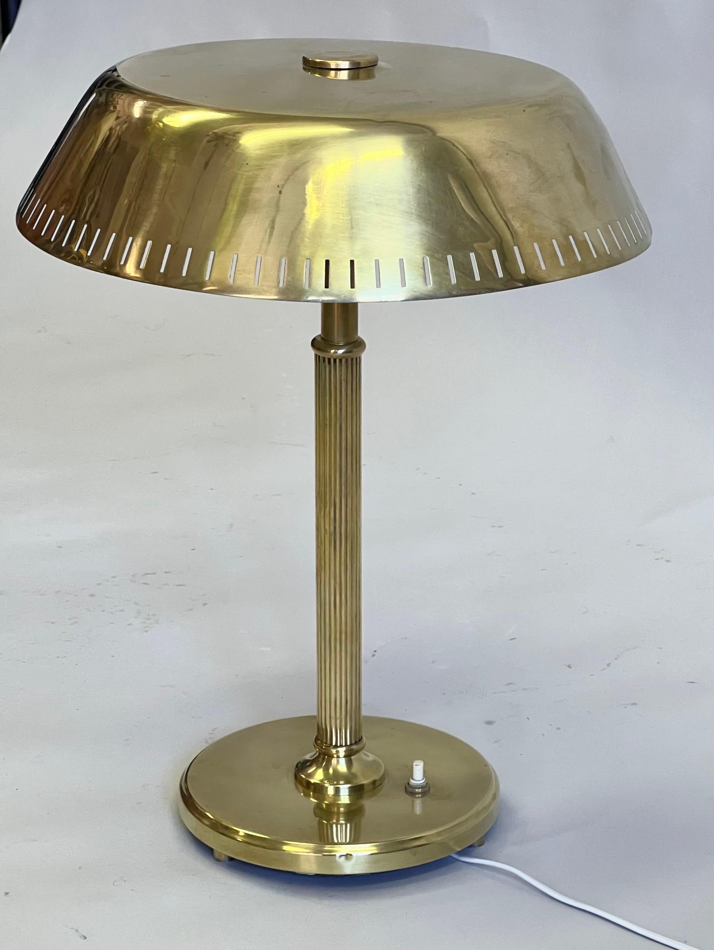 A Rare and Timeless Scandinavian Mid-Century Modern Neoclassical Desk or Table Lamp in solid brass and attributed to Paavo Tynell for Taito Oy, Finland circa 1935. An elegant design piece composed of a round. circular base delicately elevated on 3