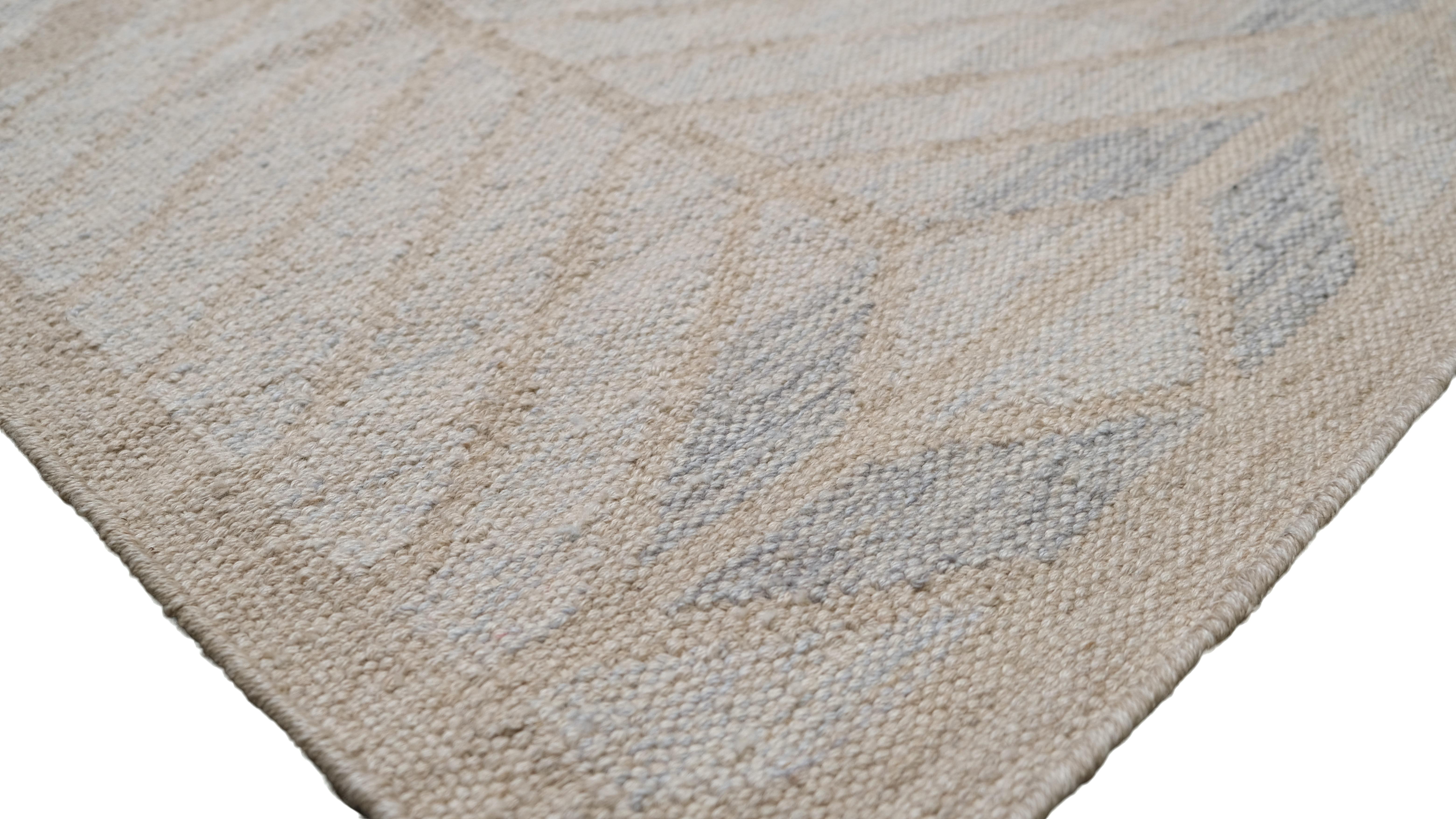 Dieser exquisite, handgewebte Wollteppich mit seinem raffinierten, geometrischen Chevron-Muster in sanften, neutralen Tönen wertet Ihre Einrichtung auf. Das raffinierte Design mit subtilen Beige-, Elfenbein- und Hellblautönen sorgt für eine