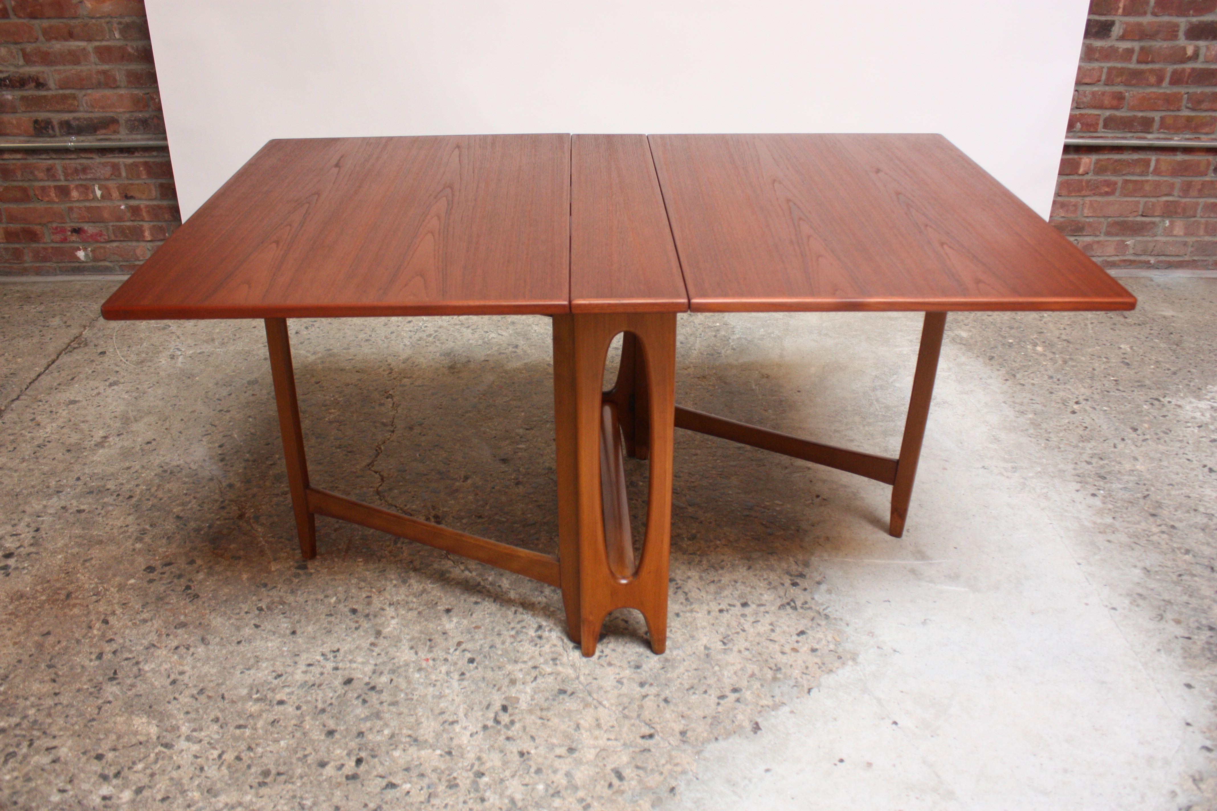 1960s Scandinavian dining table, featuring gate-leg / drop-leaf construction with a stained oak top and beech base. Bears a small footprint when leaves are down and stores away easily when not in use; when fully extended, seats six. Simple to use,