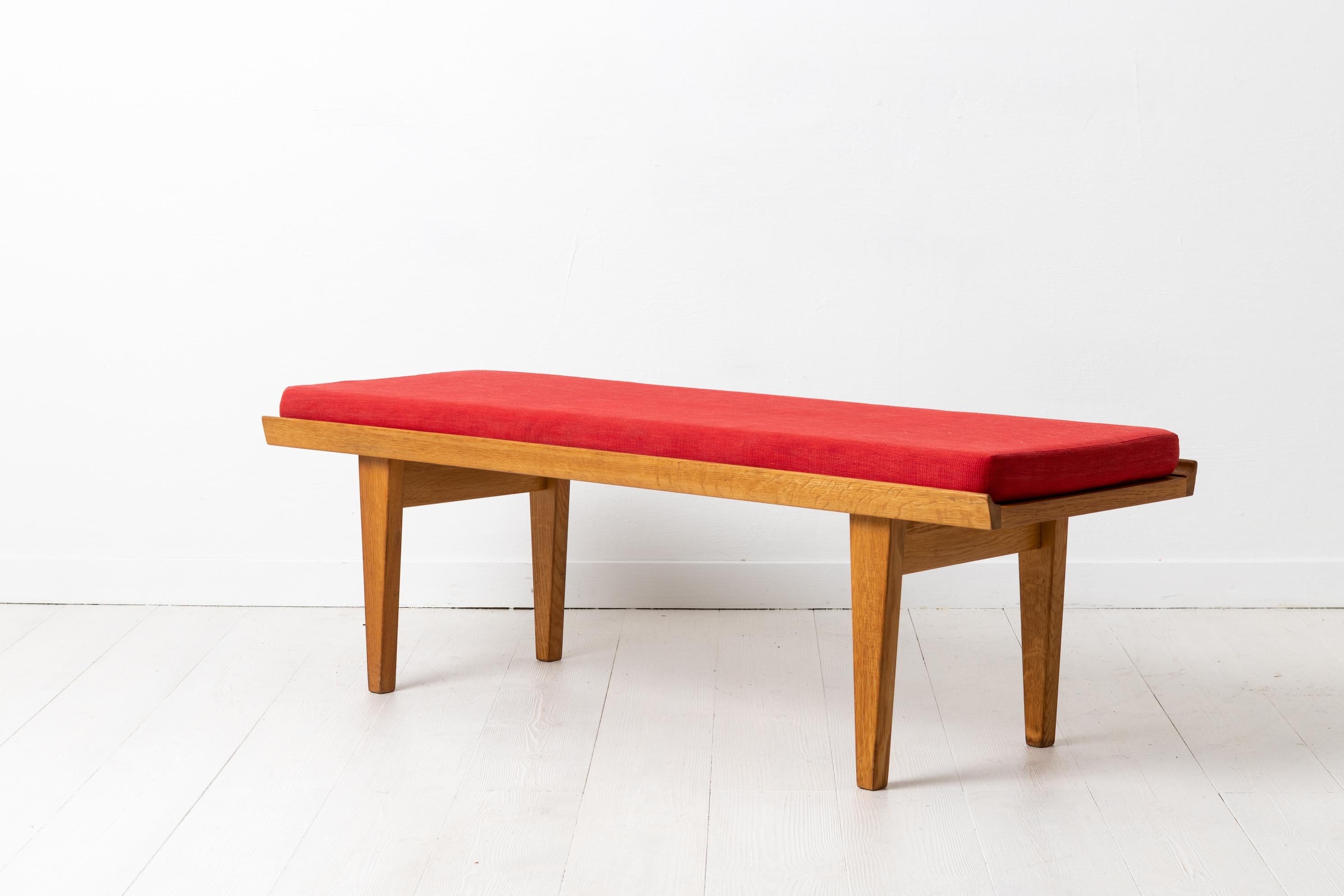 Scandinavian Modern bench by Børge Mogensen for Karl Andersson & Söner from the 1960s. The bench is made in light oak with a detached cushion with red upholstery. The bench is in good vintage condition consistent with age and use. The cushion is 5