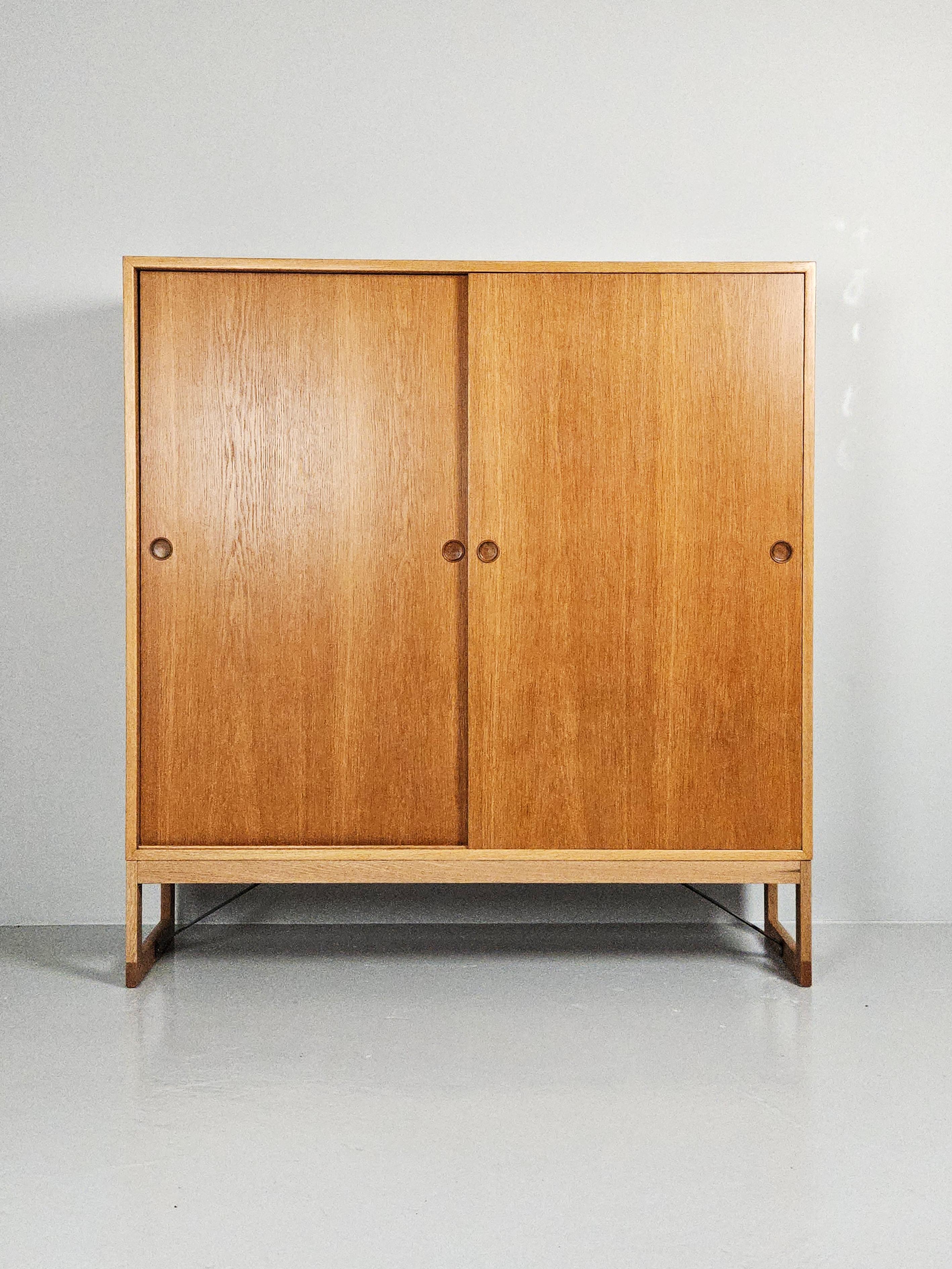 Grand meuble haut conçu par Børge Mogensen et produit par Karl Andersson & Söner dans les années 1960. 

Fabriqué en chêne avec deux portes coulissantes et des étagères mobiles. 