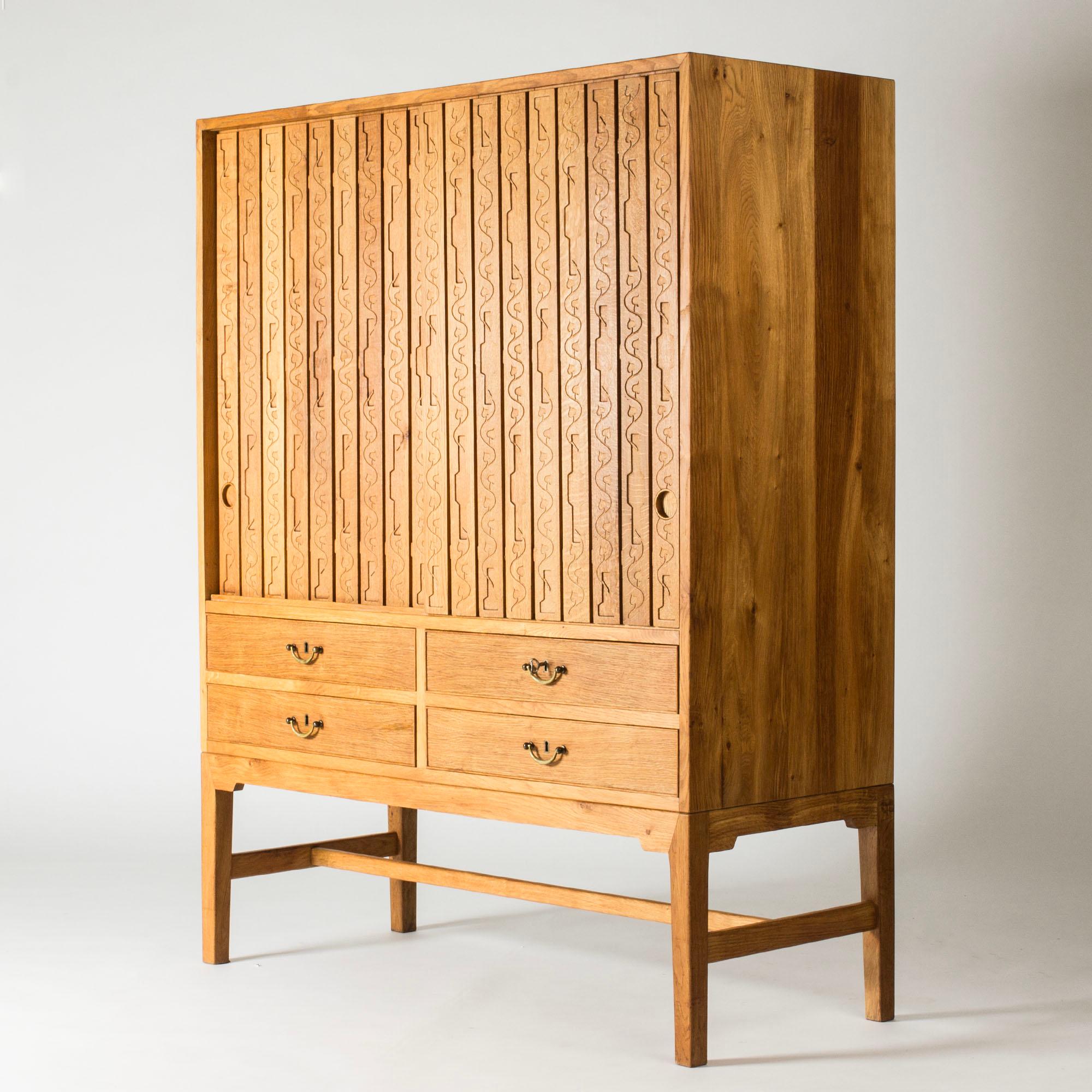 Increíble armario de Hans J. Wegner, fabricado en roble y con puertas con un elaborado diseño de bellotas en relieve y formas gráficas. Asas redondas embutidas. Los estantes y cajones ofrecen abundante almacenamiento.