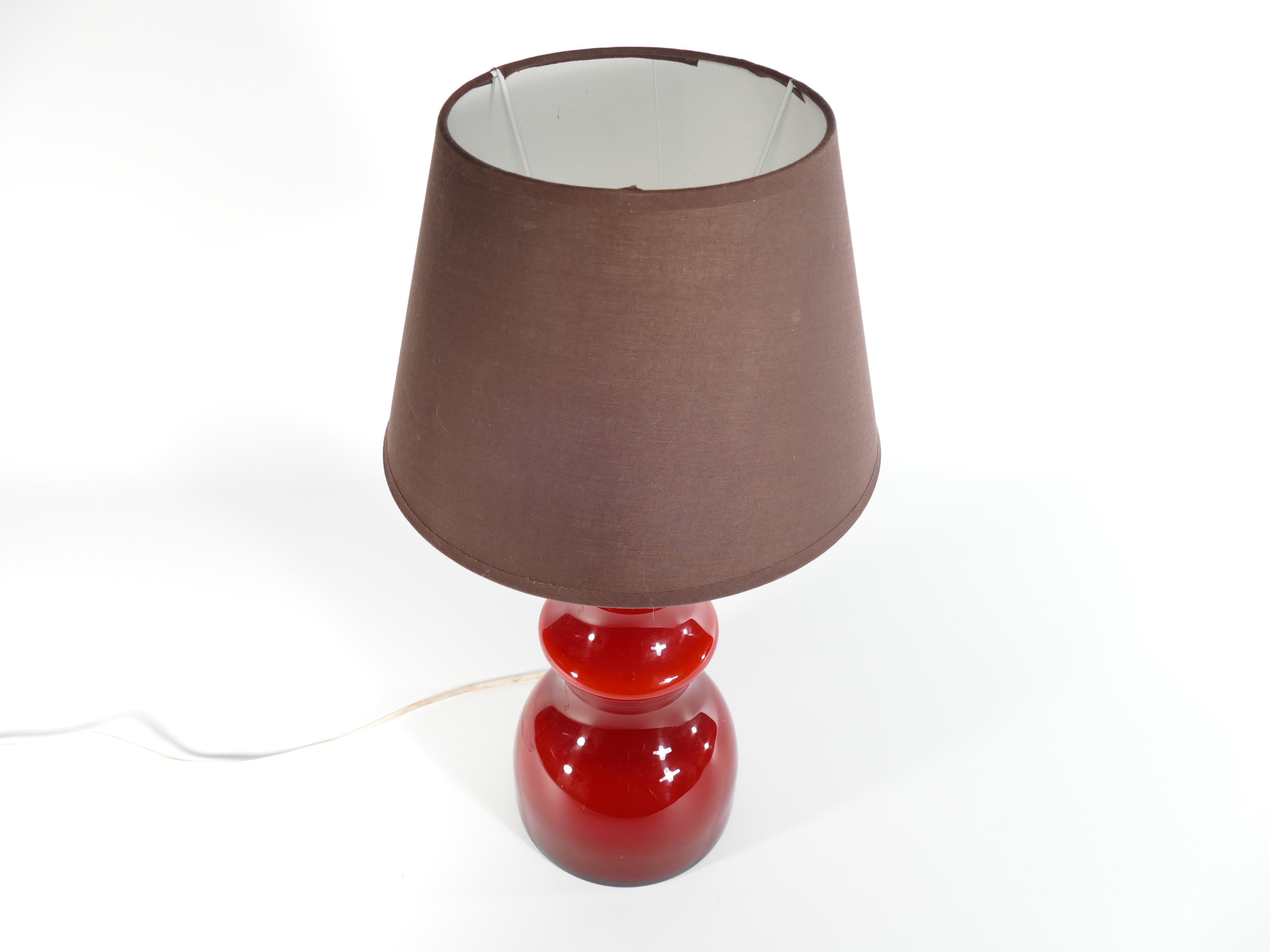 This exceptional opaline oxblood red table lamp by Gert Nyström for Hyllinge Glasbruk, Sweden, is not just a source of light; it's a statement of sophistication and timeless beauty.  

The lamp's exquisite opaline glass shade in a rich oxblood red