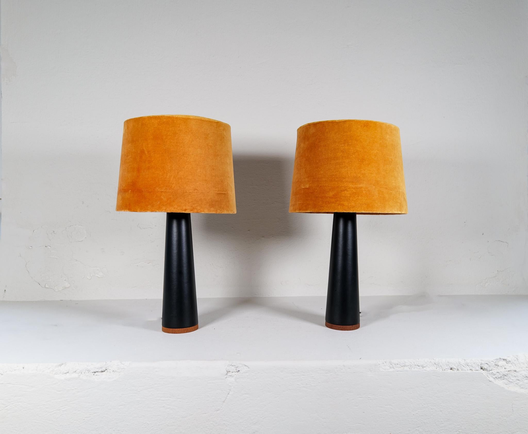 Paire de lampes de table fabriquées en Suède et produites par le célèbre Luxus. Ils sont fabriqués en cuir synthétique noir avec des coutures autour d'une base en teck. 

Belle condition vintage.

Dimensions : Hauteur 37cm, Base 11 diamètre, avec