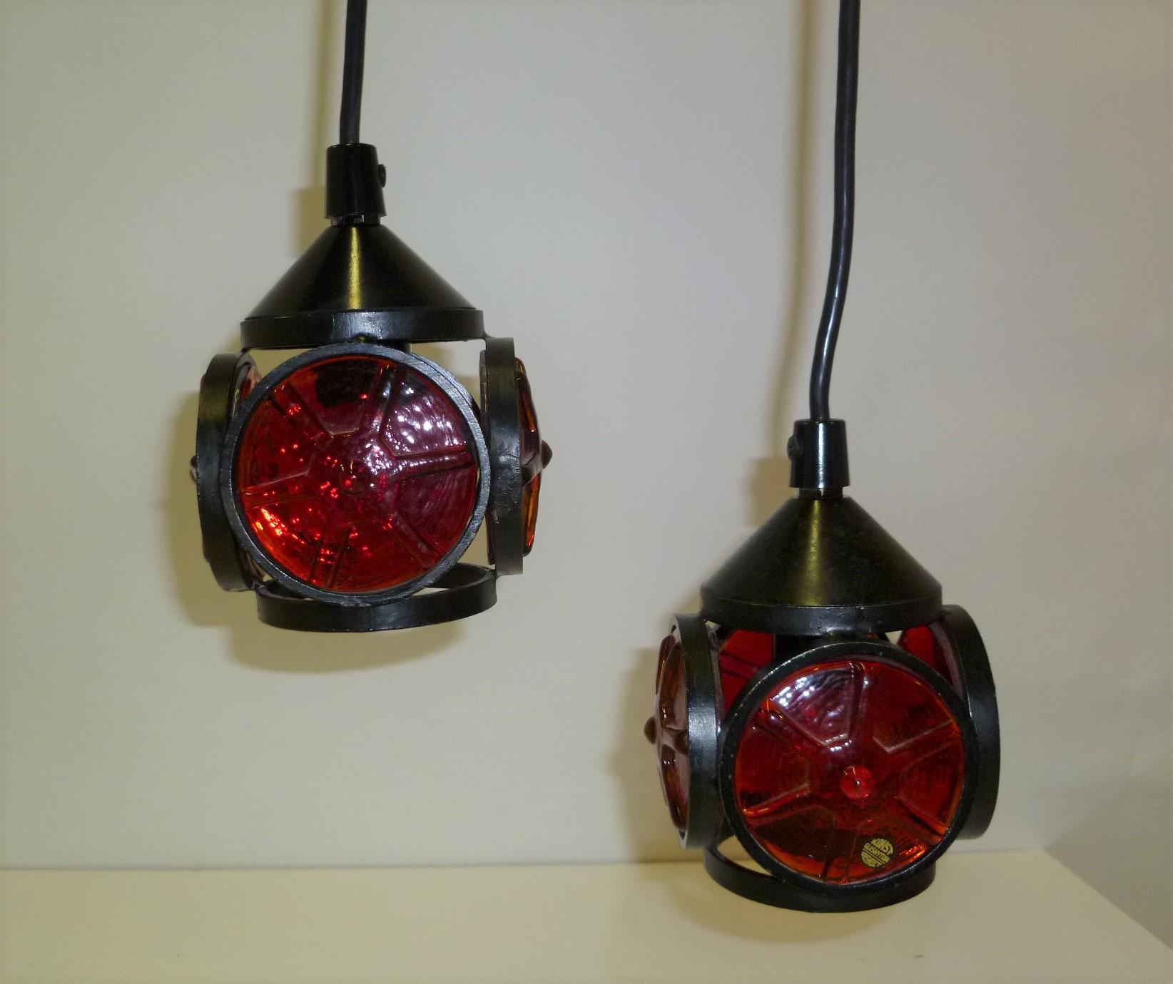 Swedish modern red glass inserts and black metal frame, a pair of small pendants by Konst Glashyttan Urschult, Sweden from the 1970s. The red glass inserts were made in the manner of Erik Hoglund, thick and heavy, and resemble the steering wheel of
