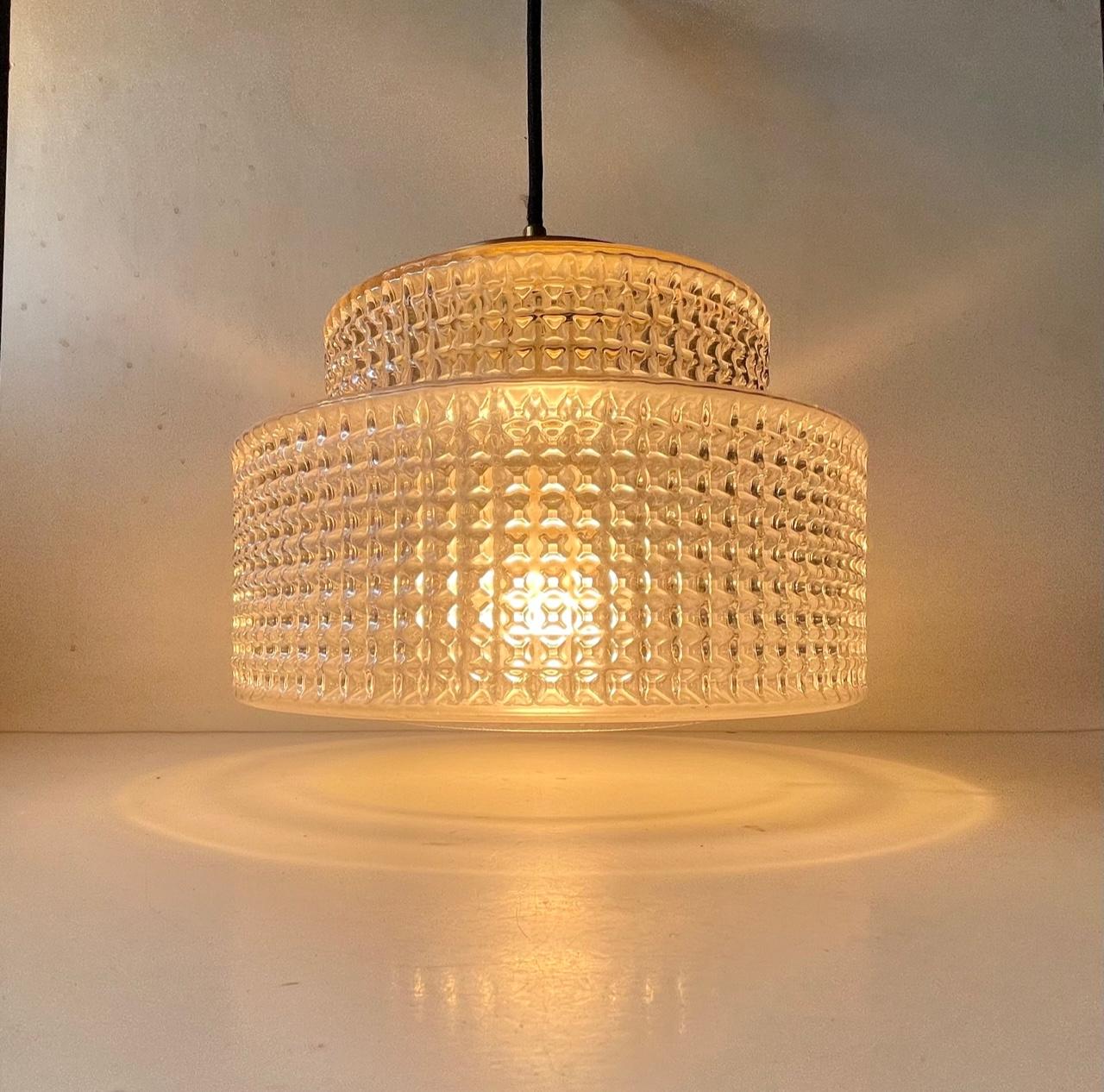 A stylish hanging light designed and manufactured by the Danish design trio Vitrika in the 1960s. The name Vitrika, or Vi-Tri-Ka means 'The three of us can do it'. The lamp features a geometric - diamond patterned clear glass shade. The top is made