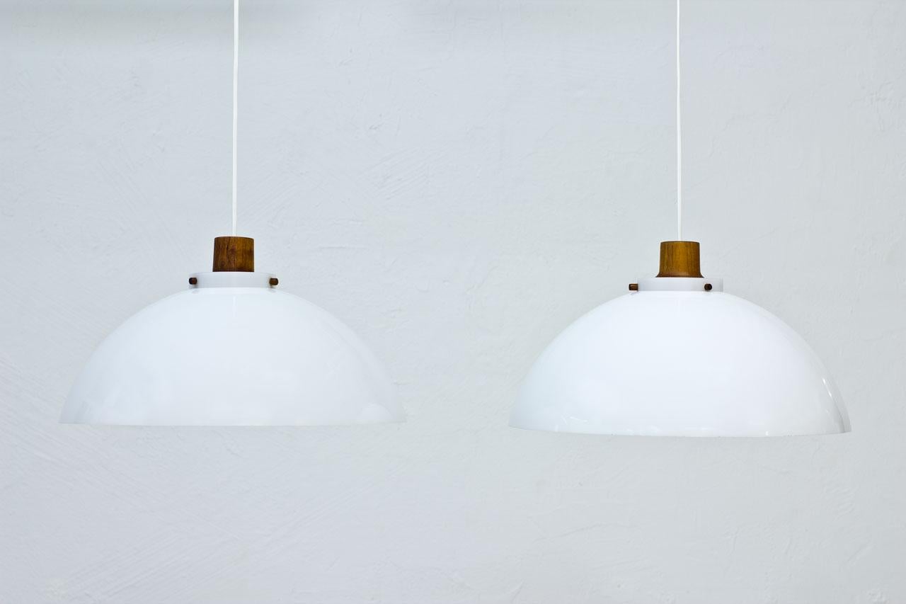 Pair of pendant lamps designed by Uno & Östen Kristiansson for their own company Luxus at Vittsjö, Sweden during the 1950s. Featured teak structure with acrylic diffuser and reflector.
