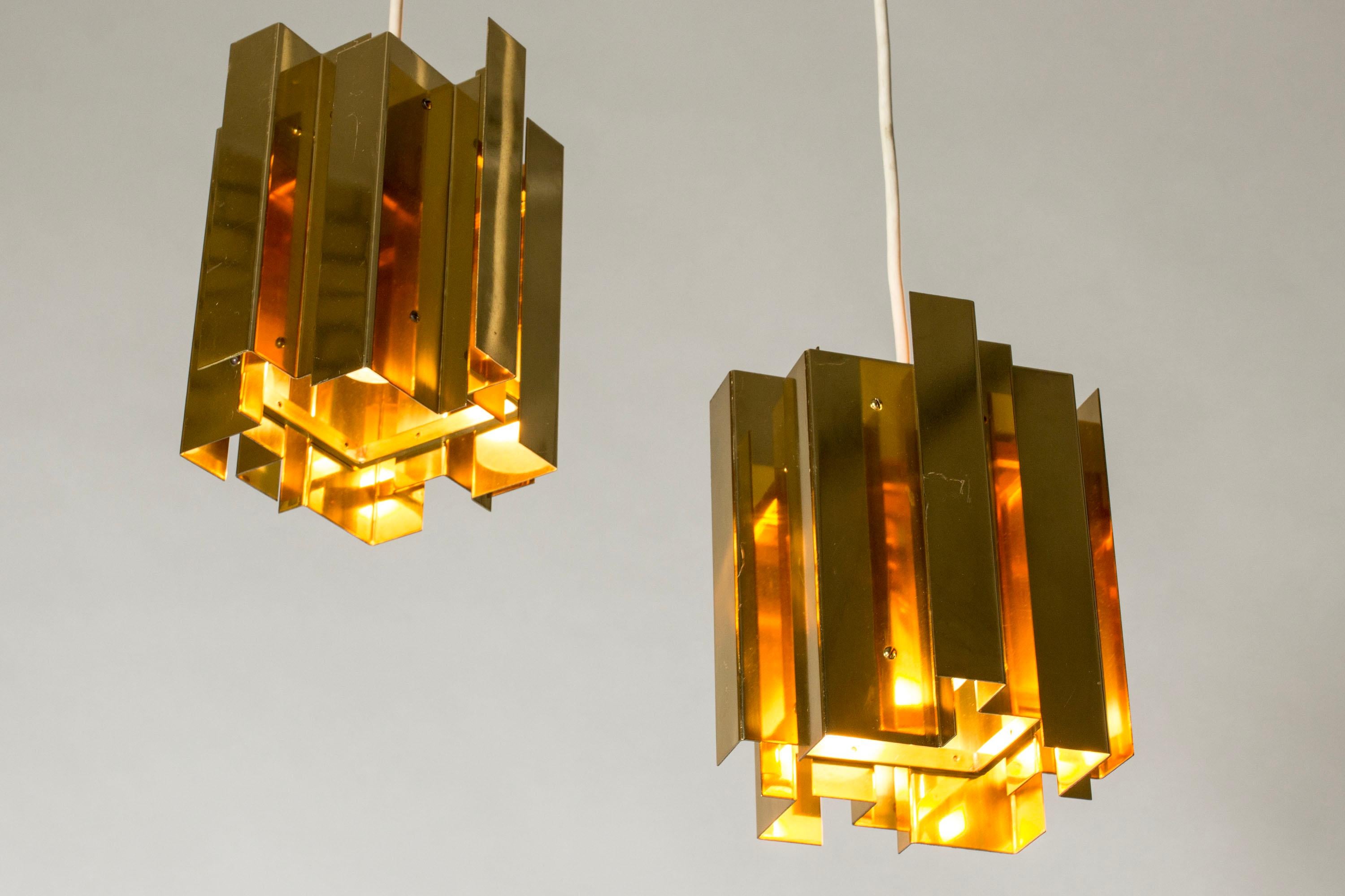 Pair of amazing modernist brass ceiling lights by Carl-Axel Acking, in a boxy design with angular folds that play with the light and let it out with a warm glow.
