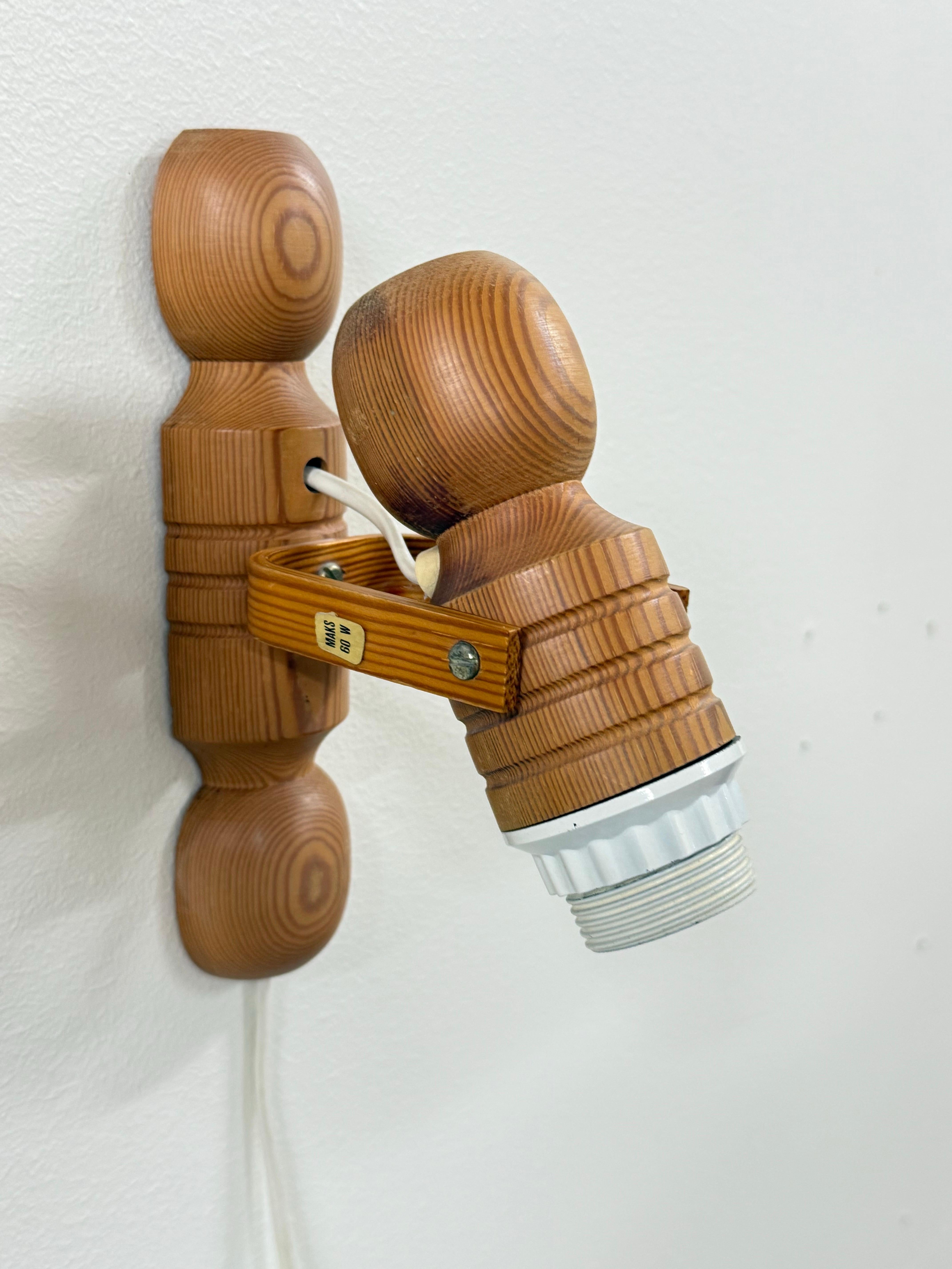 Bellissima coppia di lampade da parete vintage scandinave in legno di pino massiccio. Questi apparecchi unici sono caratterizzati da un design a bracci regolabili e da una calda tonalità di legno naturale che aggiunge un fascino rustico e senza