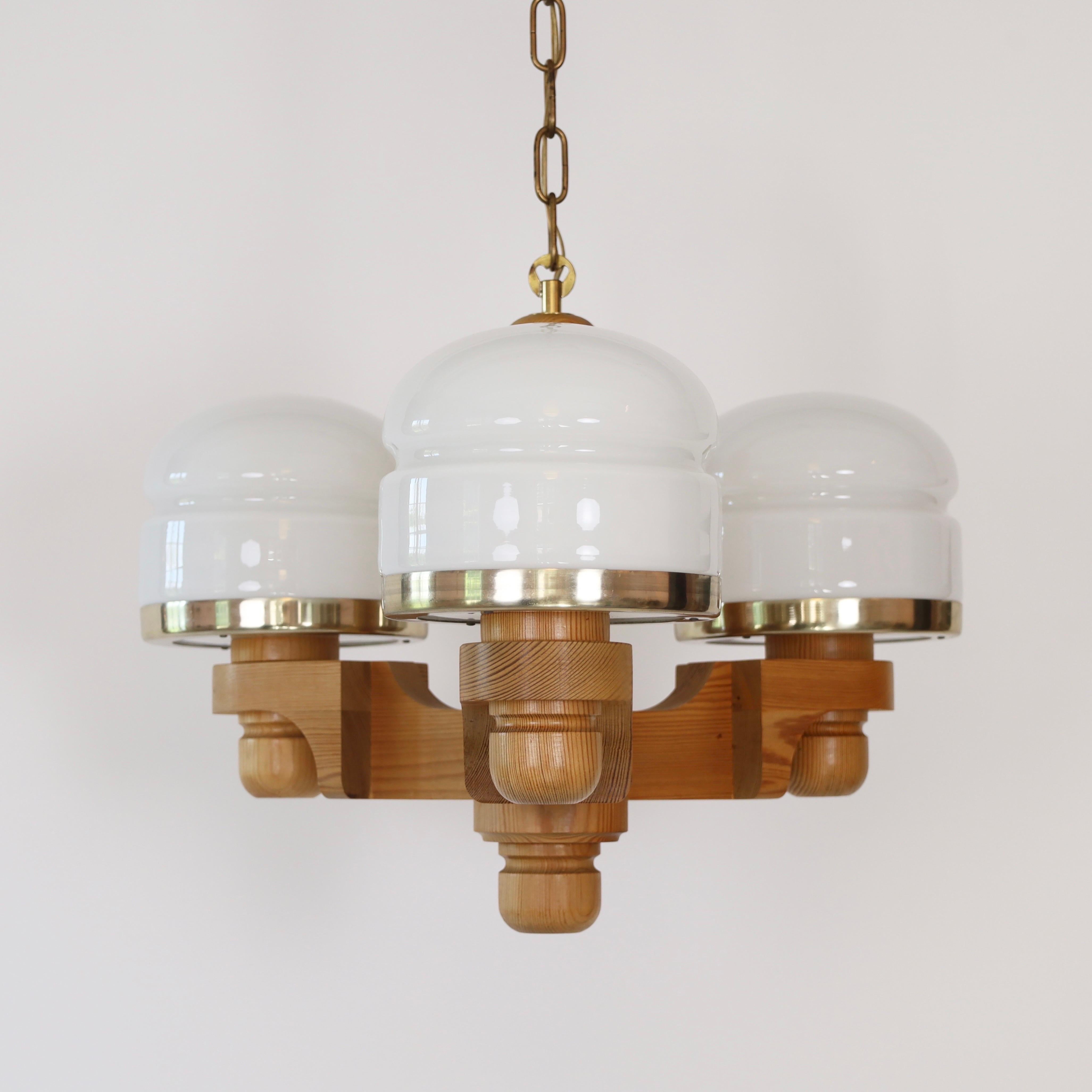 Scandinavian Modern pendant light in Pine wood with three white glass shades designed by Jan Wickelgren in the 1970s for Aneta Sweden. A center piece for a beautiful home. 

* A pendant light Pine wood with three white glass shades 
* Designer: Jan