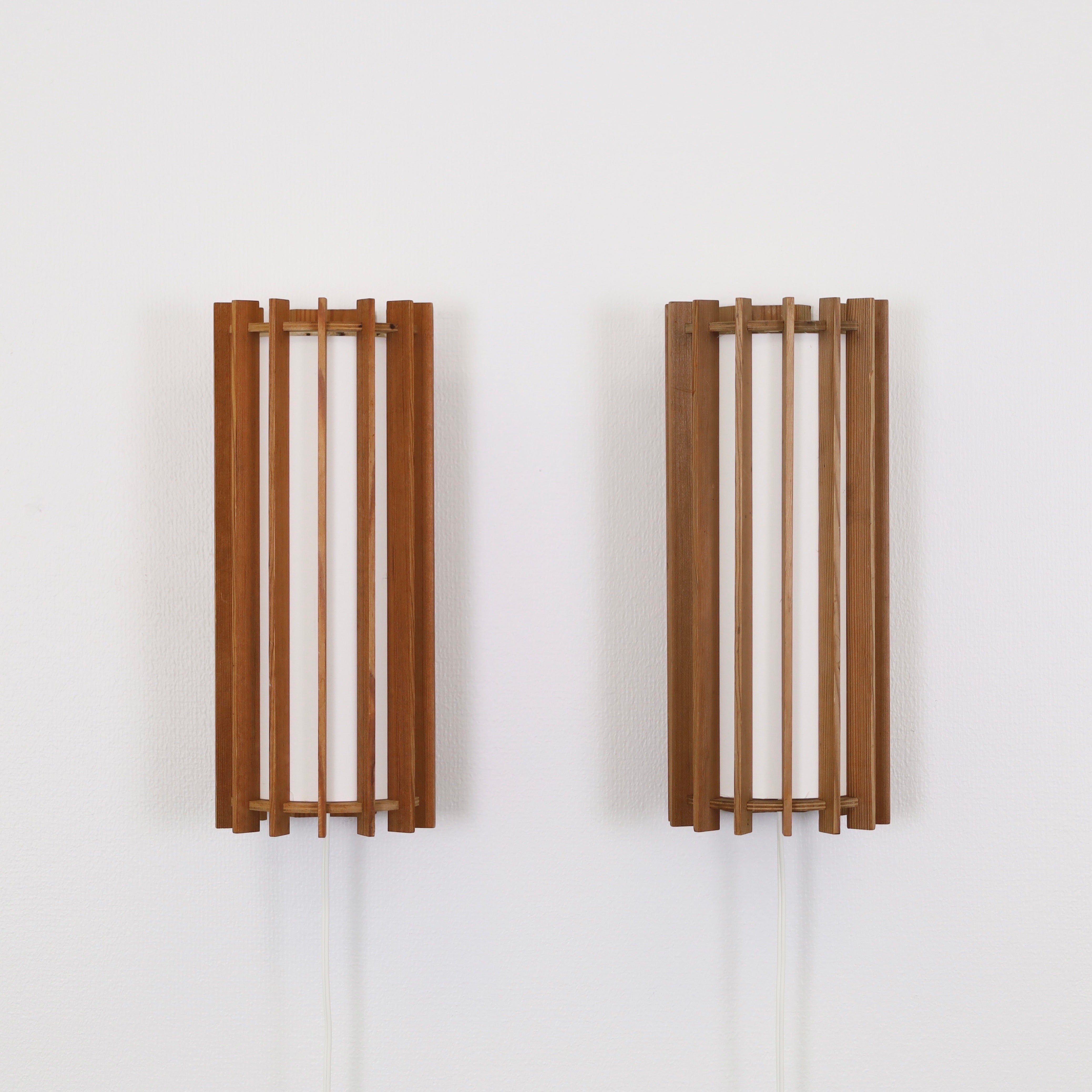 Set of Scandinavian Modern Pine Wood Wall Lamps designed by Ib Fabiansen for for Fog & Morup in the 1960s. An impressive due for an exquisite place. 

* A pair (2) of wall lamps made of vertical sticks in pine wood and with inner tubes in light