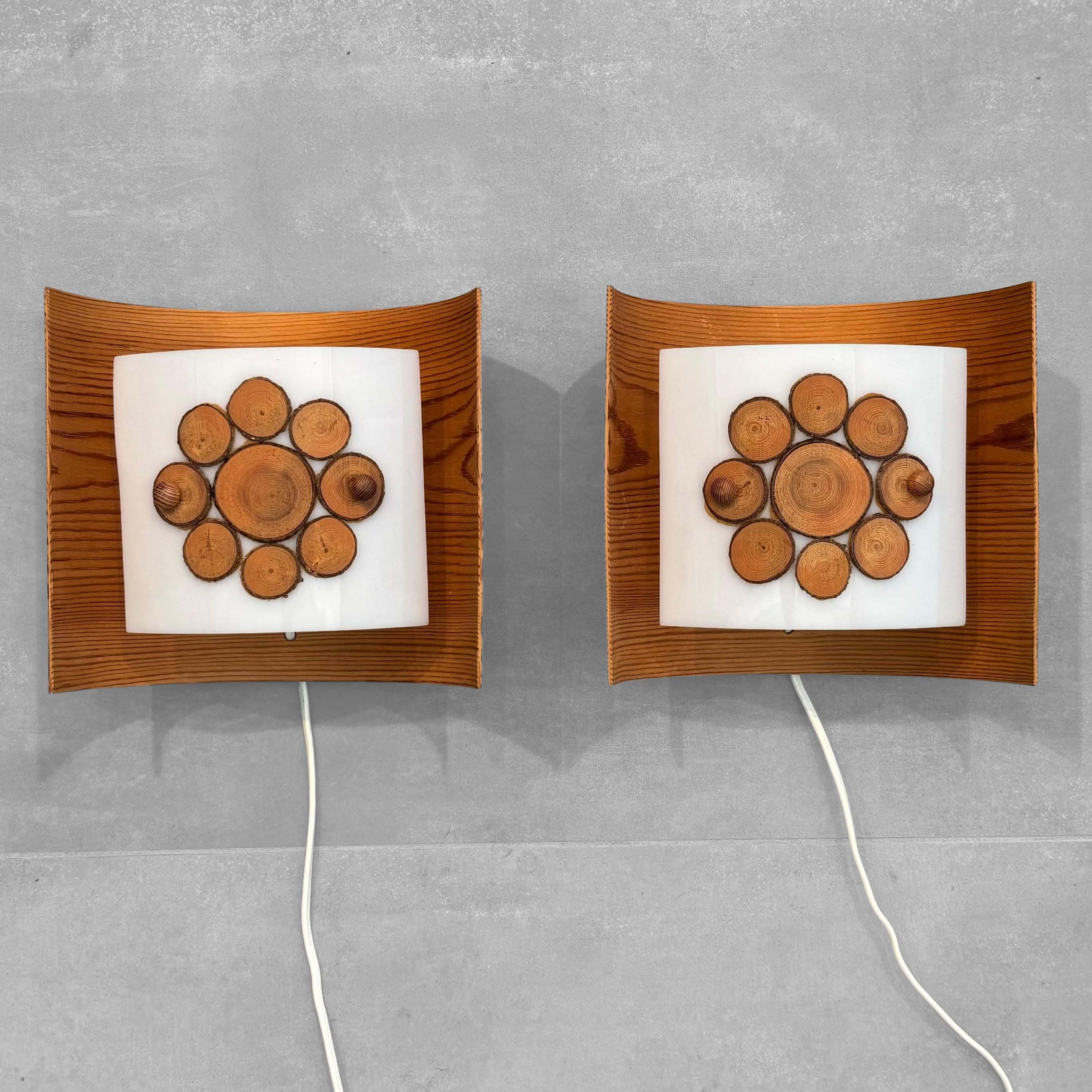 A charming pair of wall lamps, crafted by an unknown Swedish manufacturer in the 1970s. Made from moulded pinewood with a white acrylic reflector and rustic wooden details. This pair of wall scones are a great example of the rustic aesthetic typical