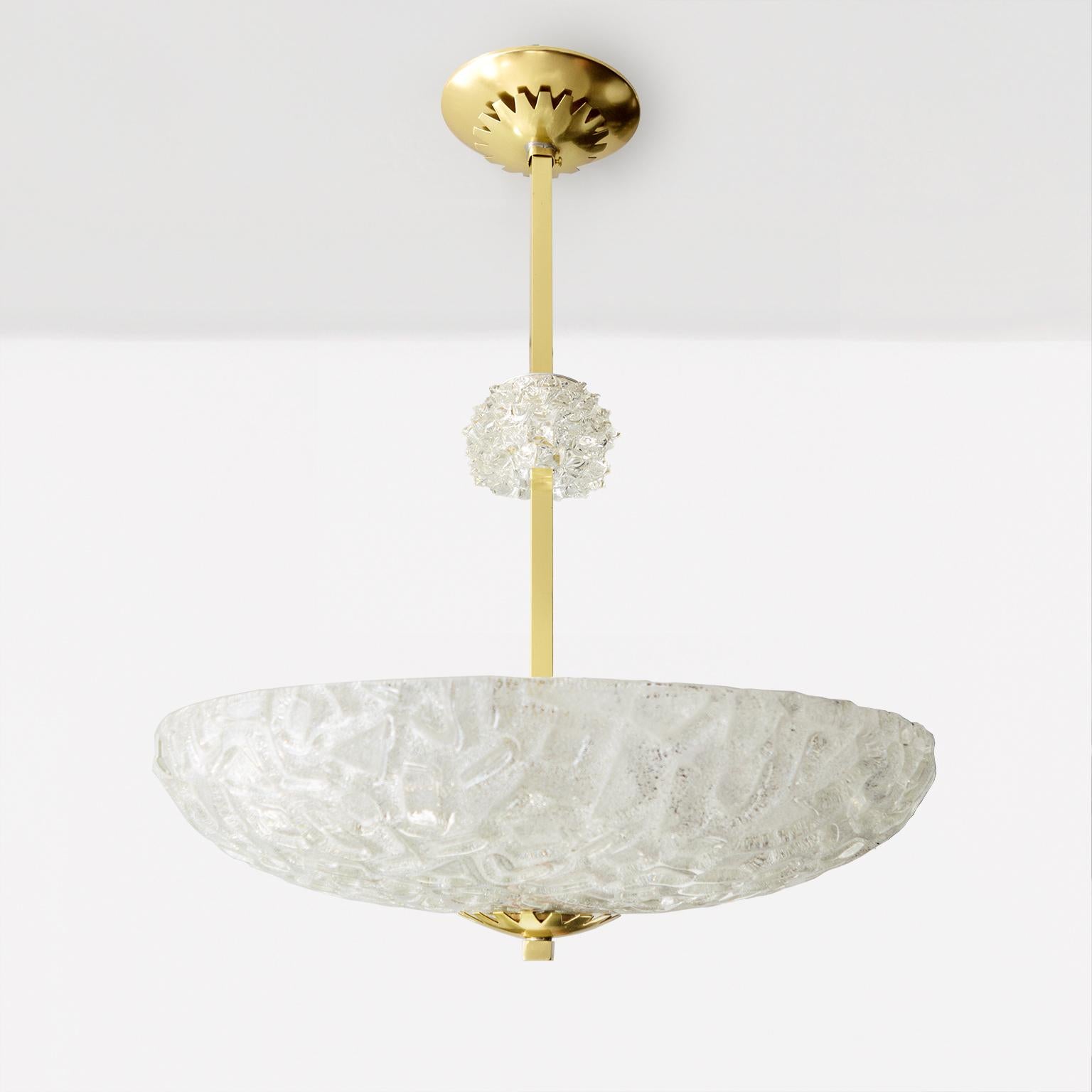 Scandinavian Modern pendant with a hand forged glass shade with icy, crystalline textures. A satellite spiky glass element hovers on the four sided brass stem. The shade’s polished brass finial is echoed just below the all brass canopy. Newly wired