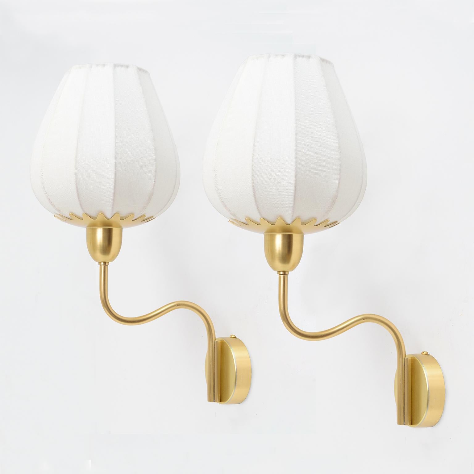 Pair of Scandinavian Modern polished brass single arm sconces with newly covered linen ribbed shades. Each scones has been fully restored and wired with a single standard base socket for use in USA. 

Measures: Height 16“ shade diameter 7“ depth