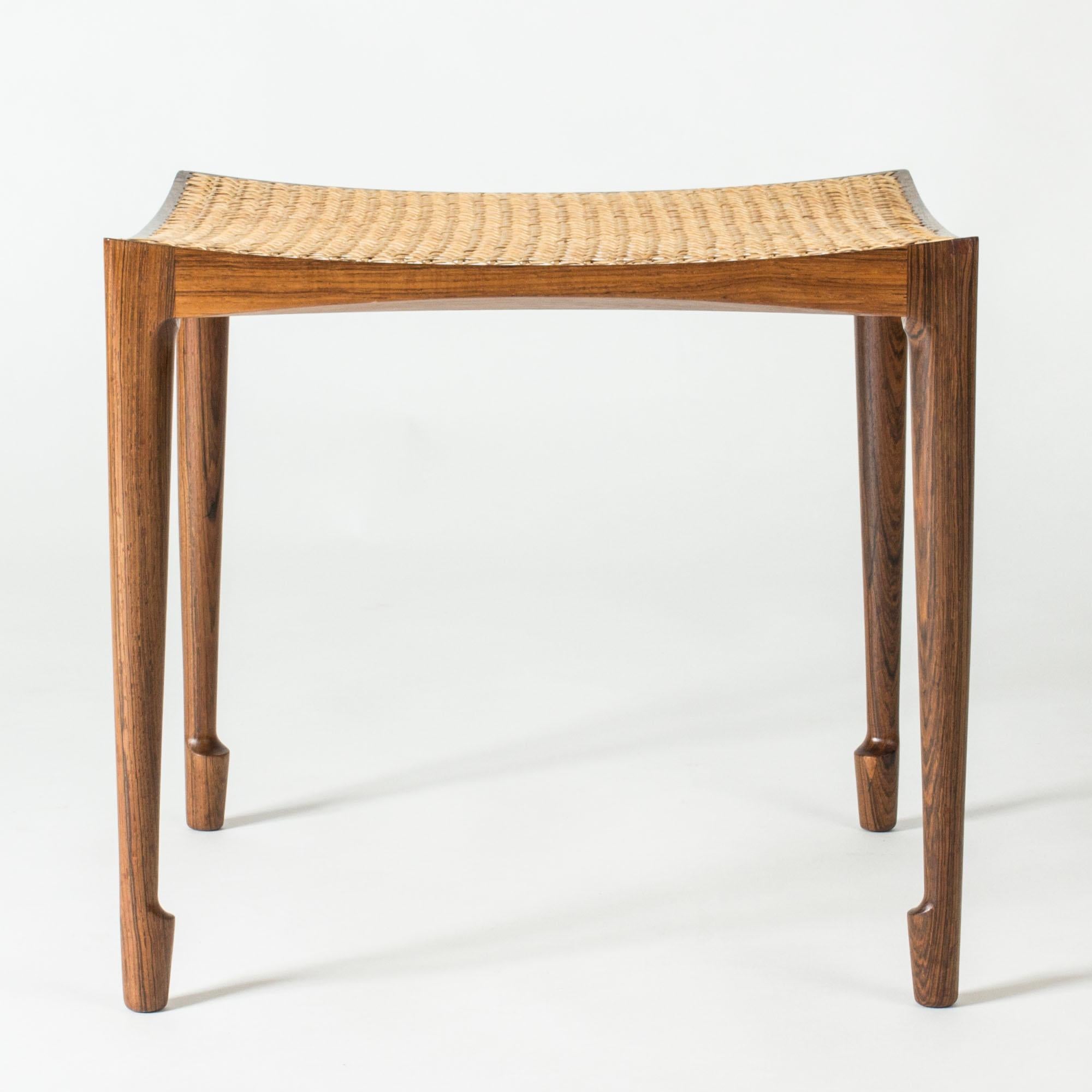 Superbe tabouret en bois de rose et rotin de Bernt Petersen. Magnifique design élancé avec des pieds sculptés et une assise subtilement concave.