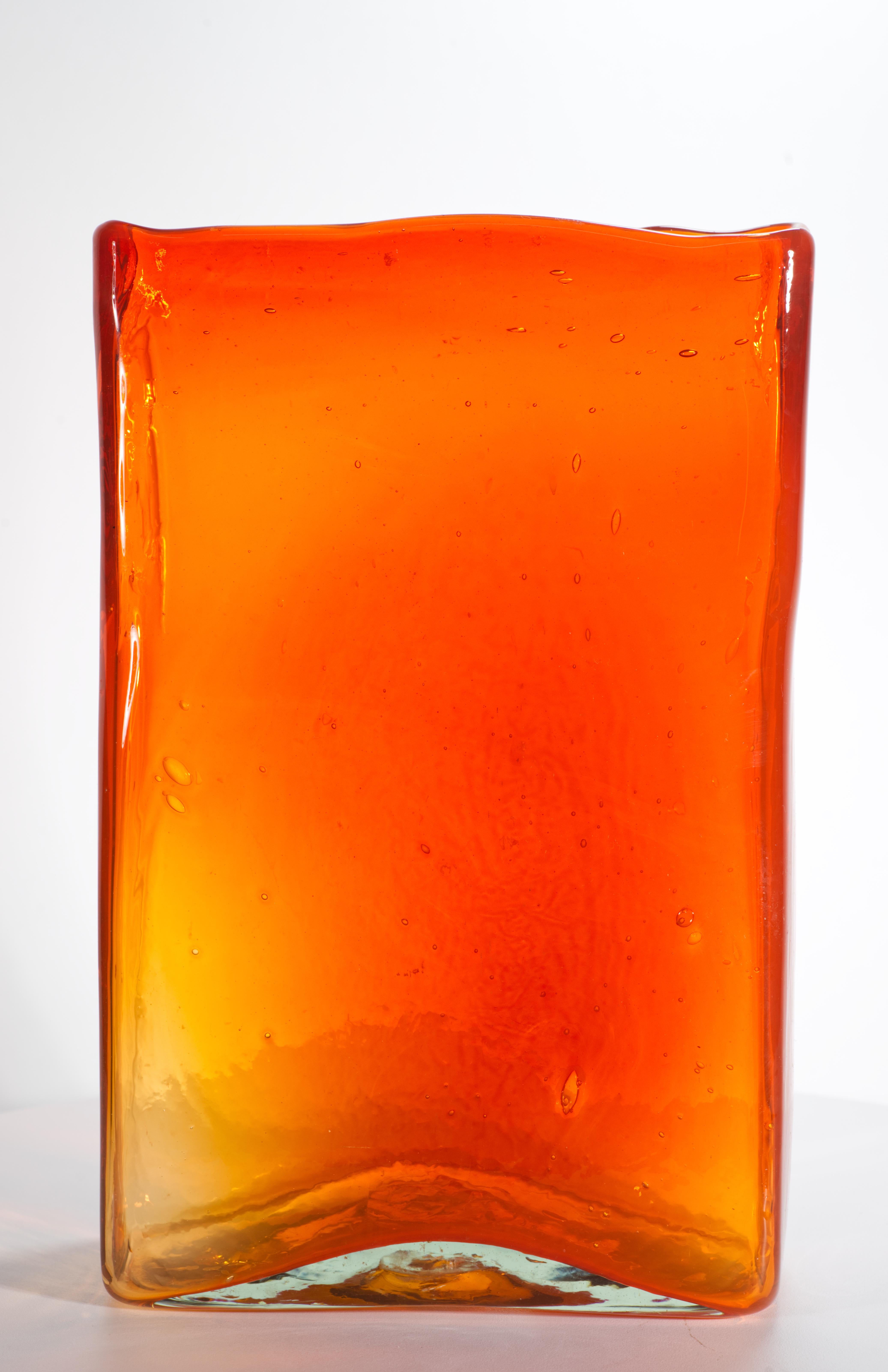  Il vaso scultoreo in vetro rettangolare è caratterizzato da un sorprendente colore arancione intenso, simile a un gioiello, e da superfici leggermente strutturate che aggiungono dettagli e interesse visivo a un pezzo dalla forma minimale. Il vaso