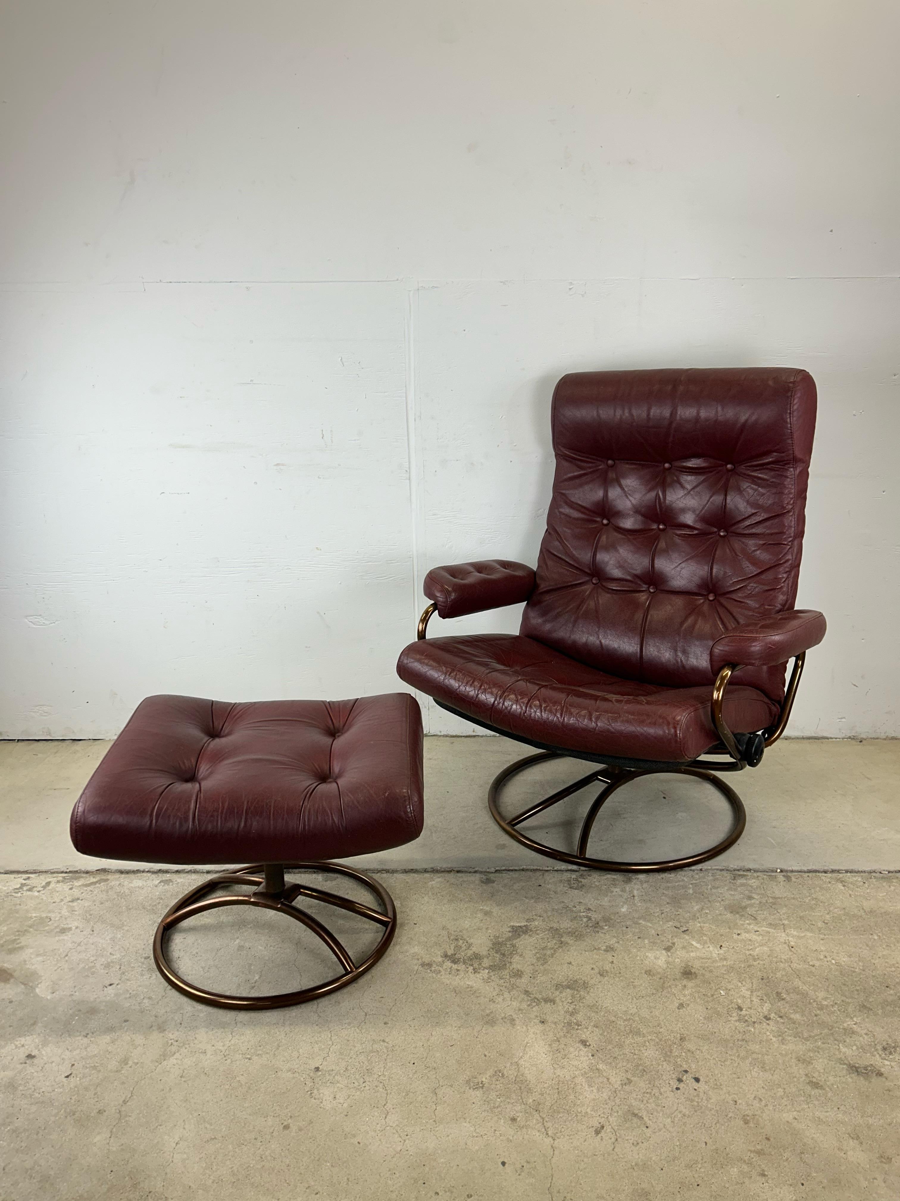 This mid century modern lounge chair by Ekornes ASA Stressless features beautiful red tufted leather seat and bronze tinted frame with swivel base.

Dimensions: 32.5w 28d 39.5h 17sh 21.5ah 
Ottoman: 21.5w 18d 15.5h 

Condition: Excellent vintage