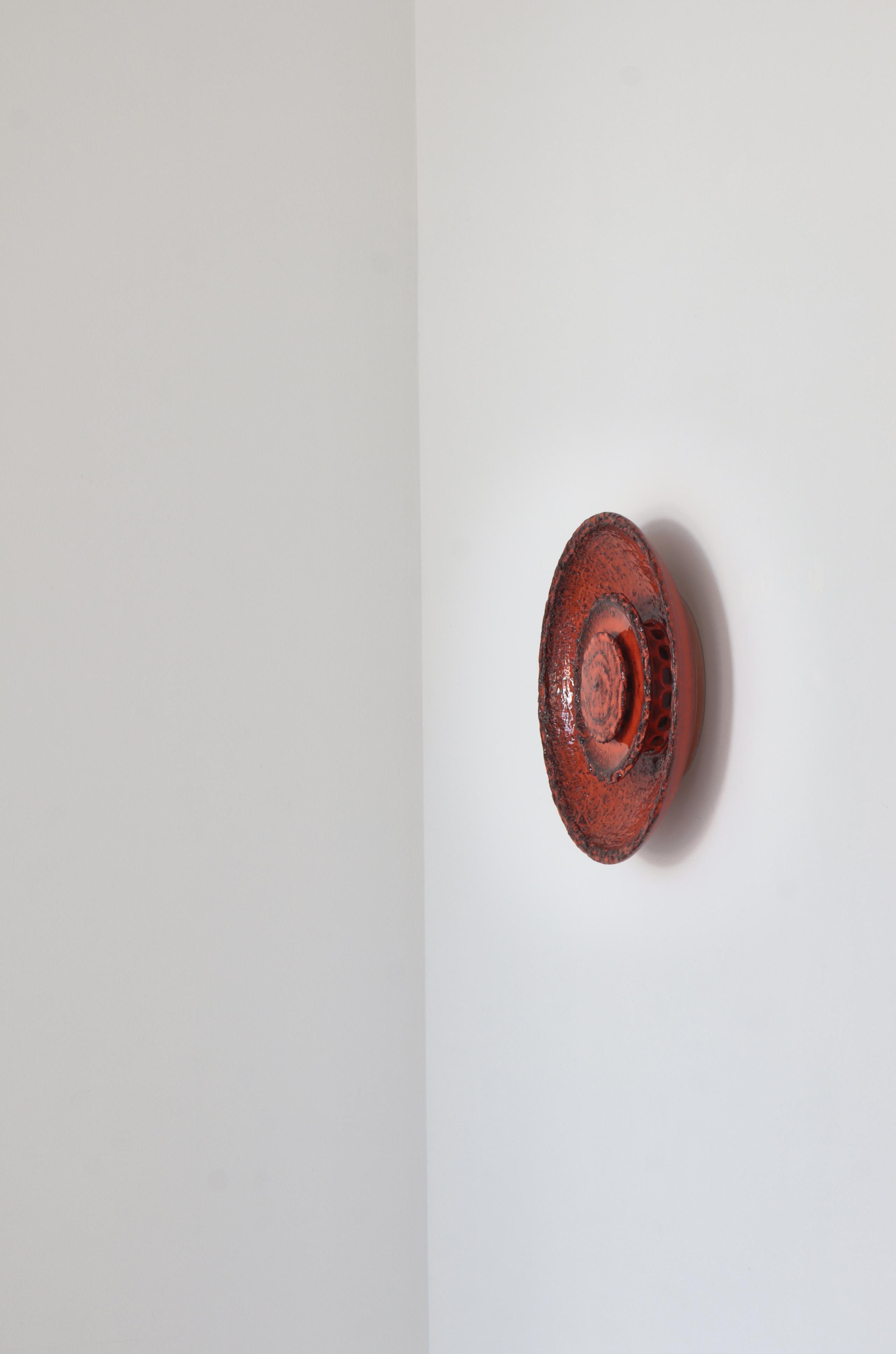 Large stoneware wall sconce in red glazing by Carl Johan Ege Nielsen for Dagnæs, Denmark. The lamp is made of a large bowl with two smaller discs inside. The light shines through round holes behind the discs, giving it a stunning light effect.
