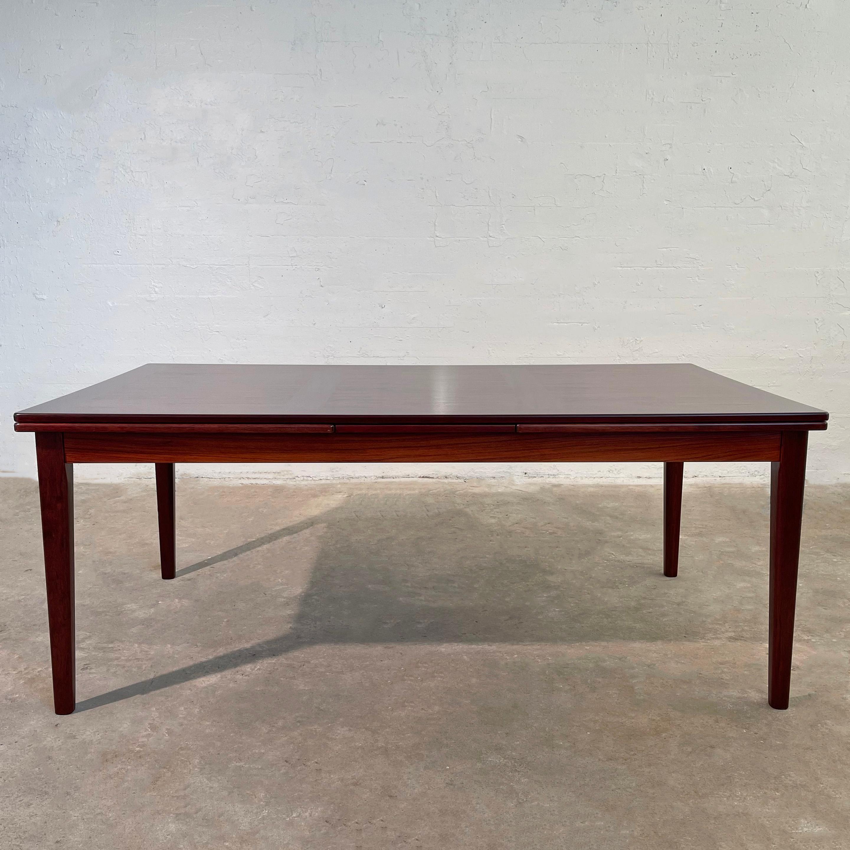 Scandinavian modern, rosewood, extension dining table by Danish maker Scovby Mobelfabrik features two 27.5 inch leaves that are stored within the table at each end to extend from 71 to 126 inches. The table has an exceptional rosewood grain with a