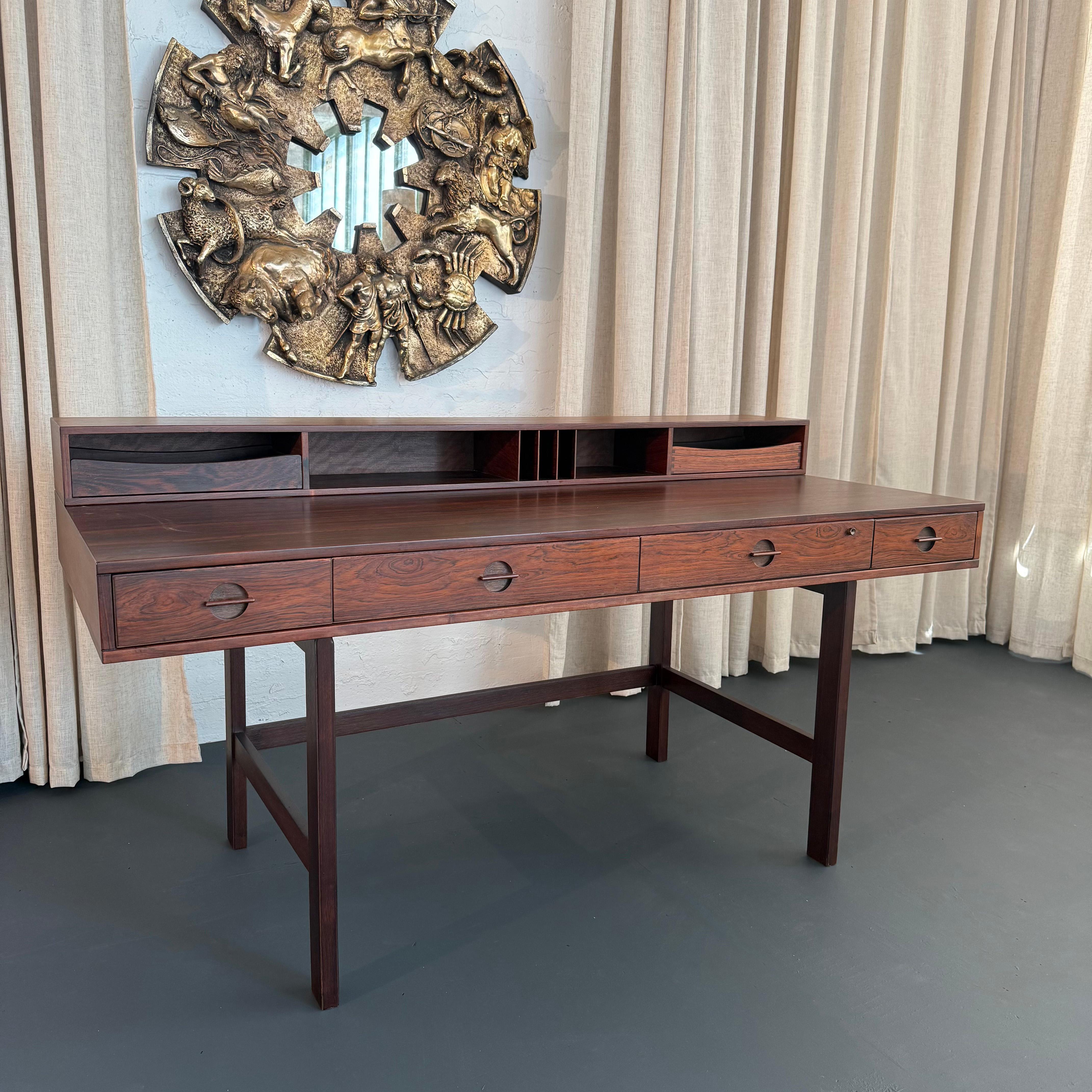 This spectacular Danish rosewood desk was designed circa 1960s by Peter Løvig Nielsen. The desk features stunning details throughout with beautiful rosewood grain, recessed circular drawer pulls and brass hinges. This ingenious design is extremely
